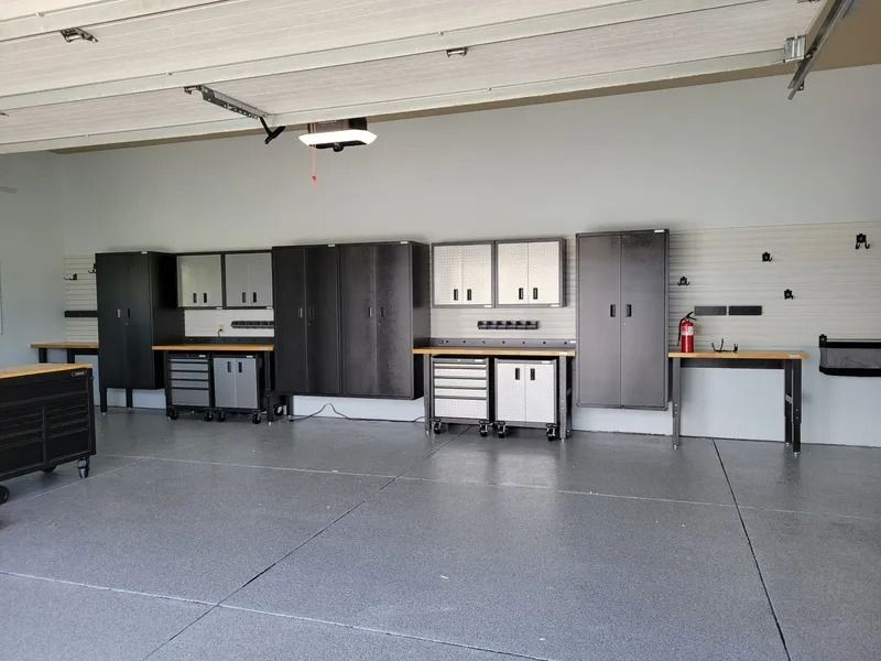 Garage interior with gray epoxy flooring, cabinets, and workbenches along the walls.