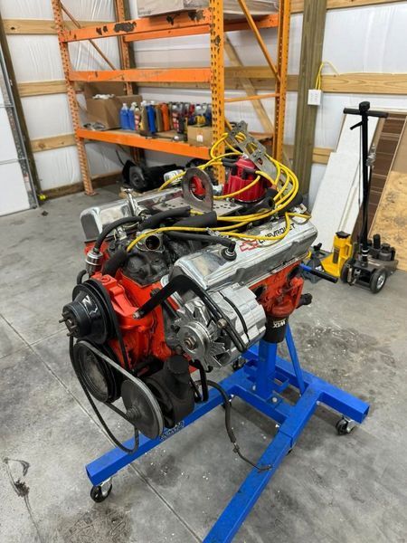 Red and black car engine on a blue stand in a garage.