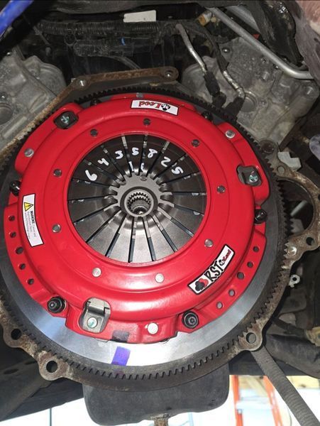 Red clutch assembly installed on an engine, viewed from below.