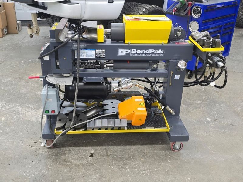 BendPak tube bender machine with a yellow and gray color scheme, set in a garage.
