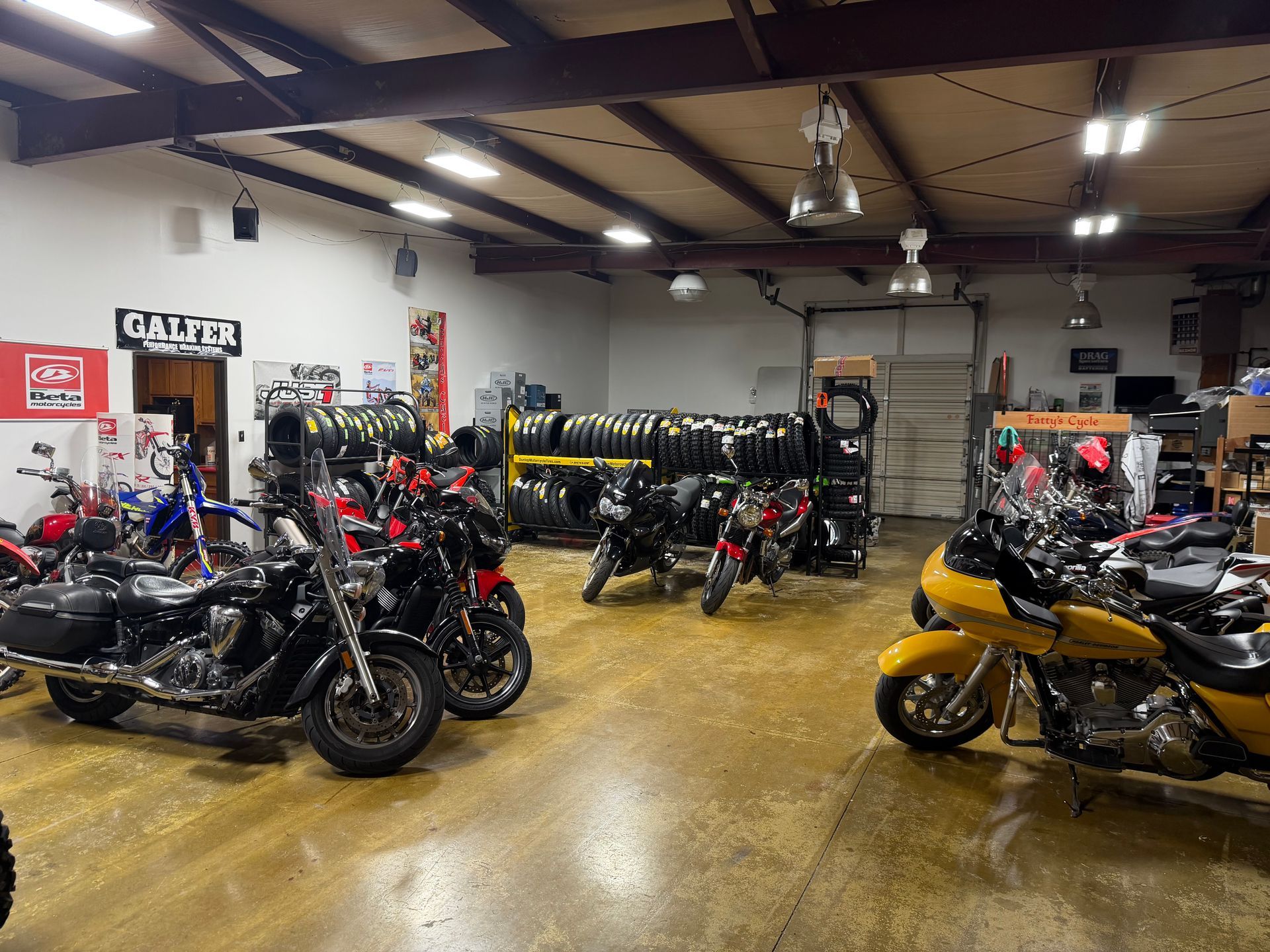 Motorcycle showroom with rows of bikes, including black and yellow models, under bright ceiling lights