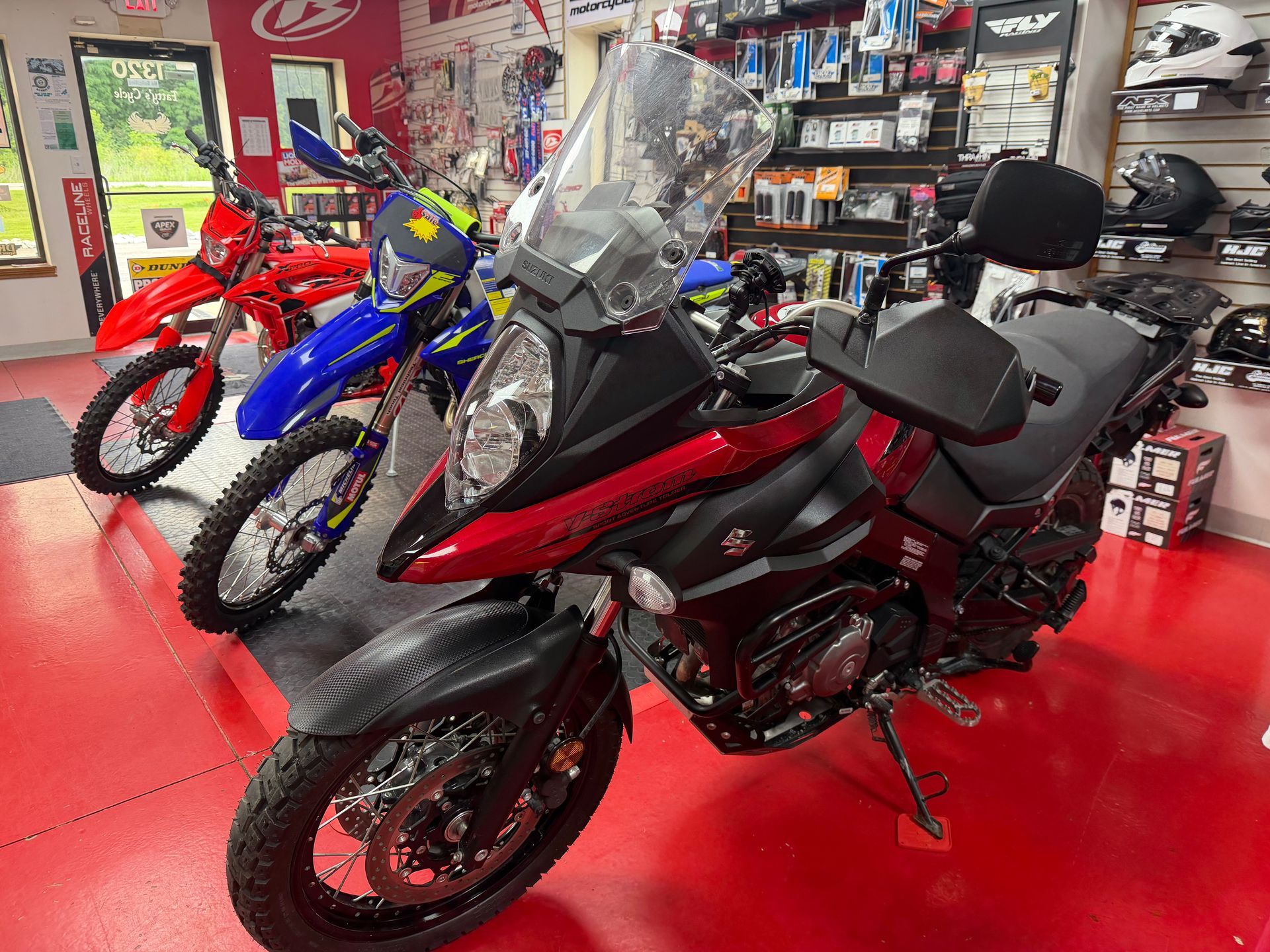 Black and red touring motorcycle on a showroom floor, with other bikes in the background.