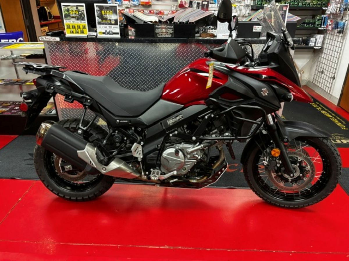 Red and black sport motorcycle displayed on a showroom floor with a red mat underneath.