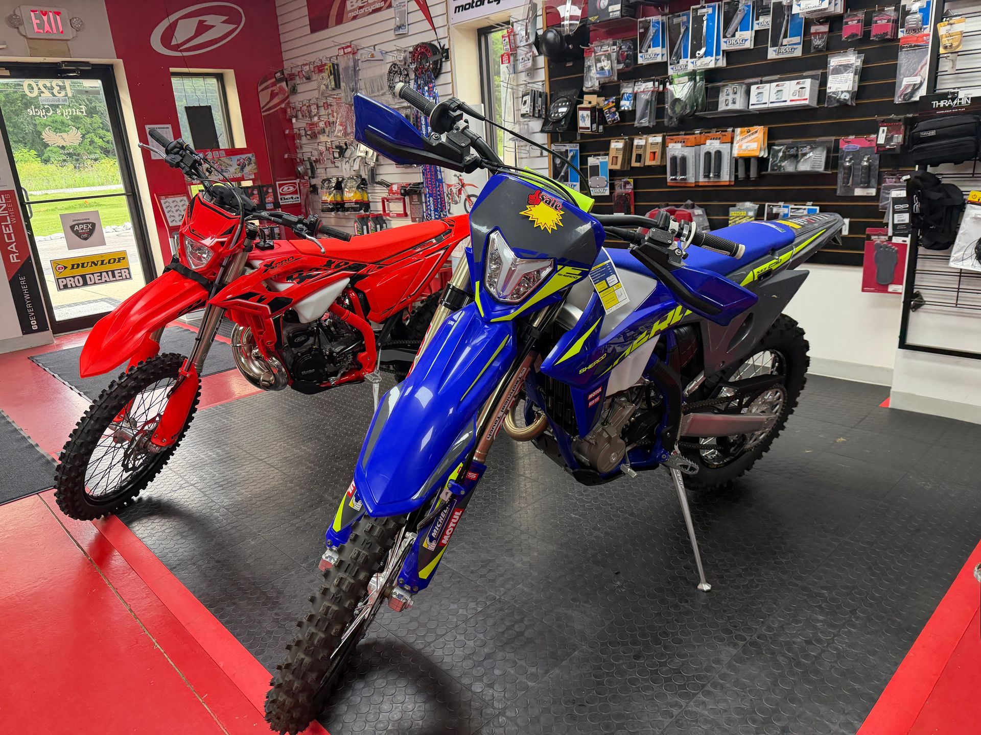 Blue and red dirt bikes on display in a motorcycle shop showroom