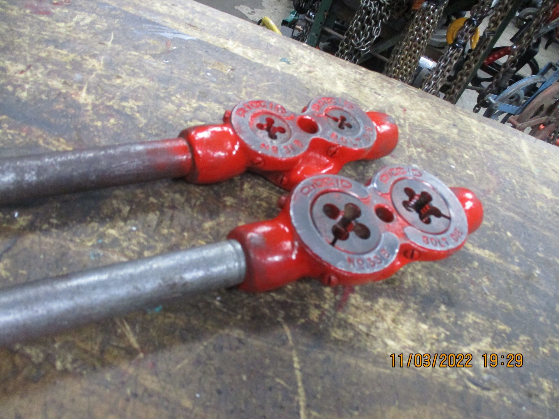 A pair of red pipe wrenches are sitting on a wooden table.