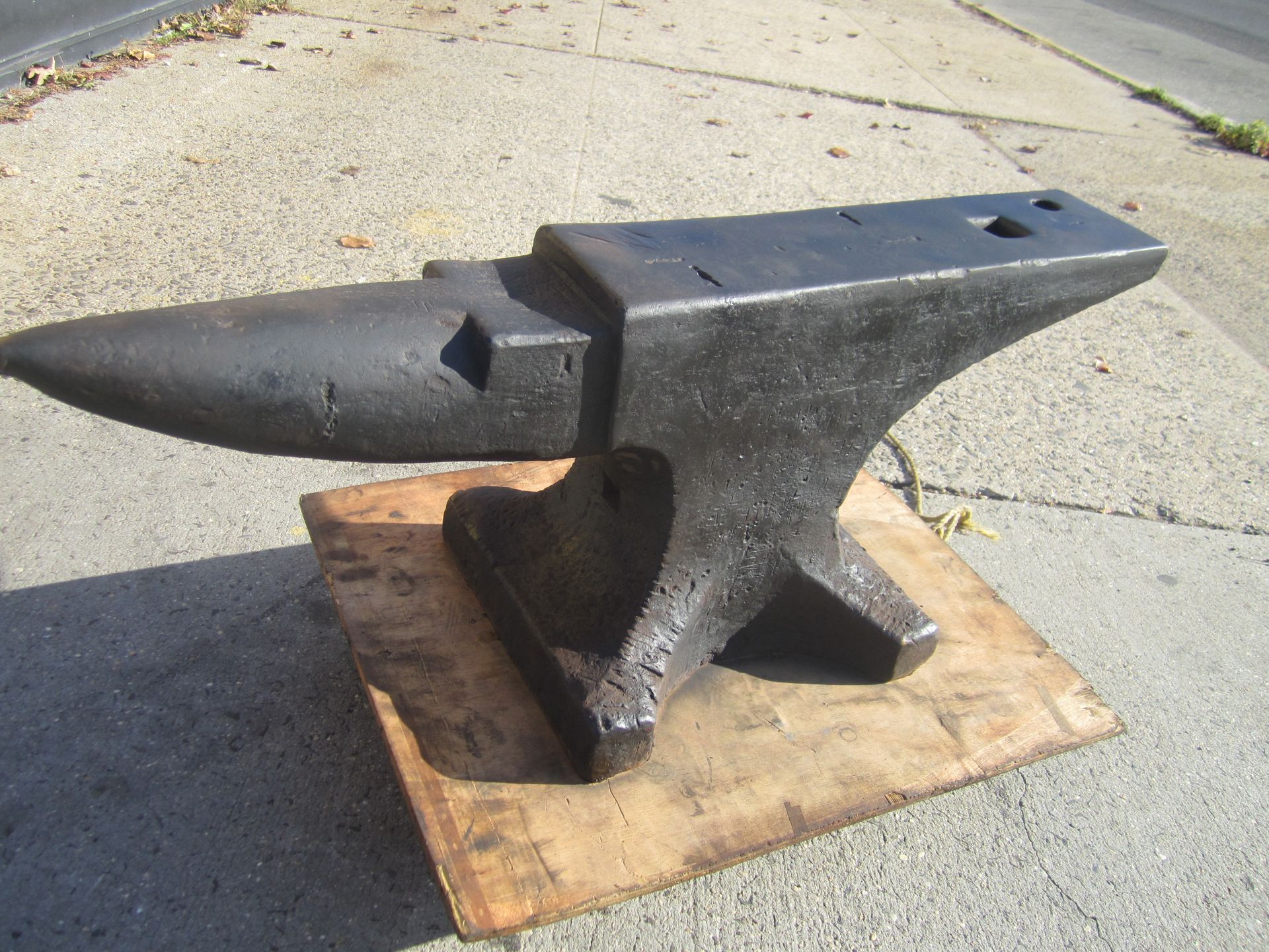 A large black anvil is sitting on a piece of wood