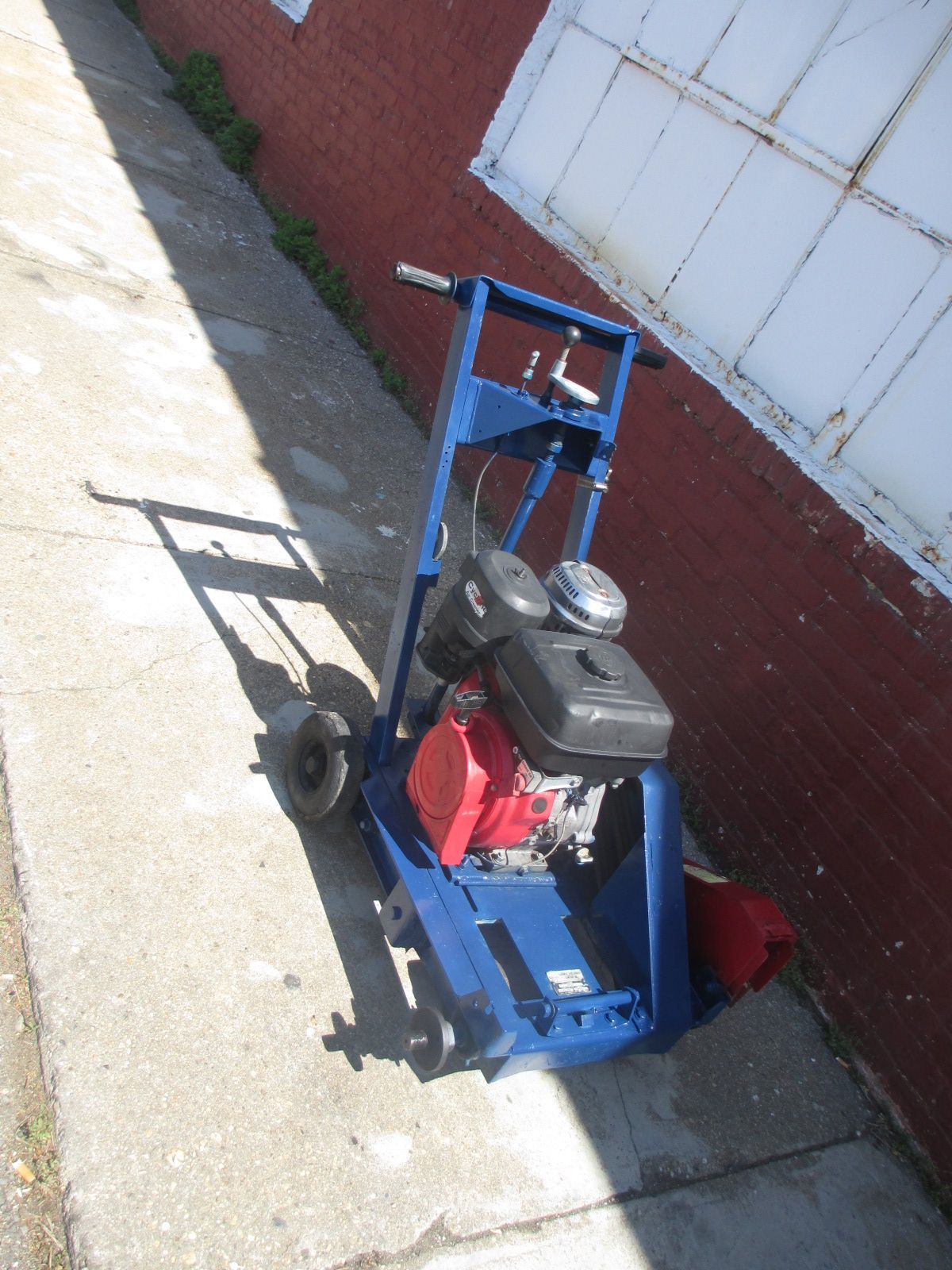 A blue machine with a red engine sits on a sidewalk