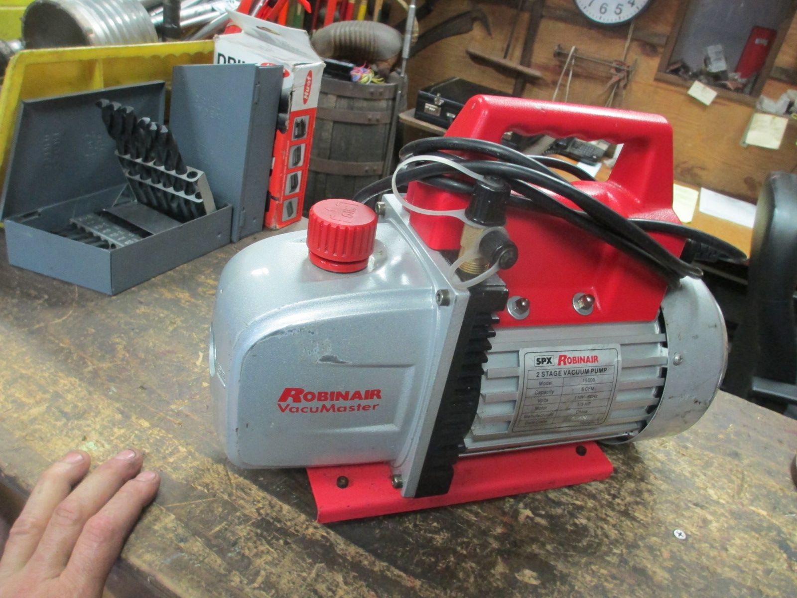 A red and silver vacuum pump is sitting on a wooden table