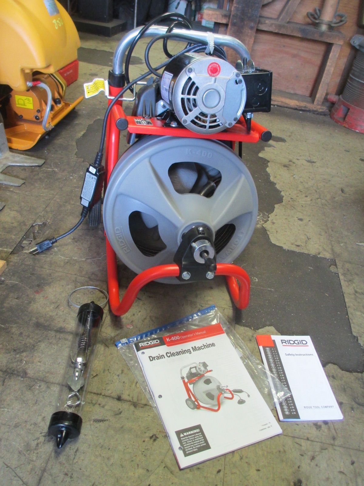 A drain cleaner is sitting on the floor next to a manual