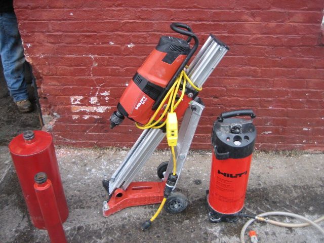 A red drill is sitting next to a vacuum cleaner