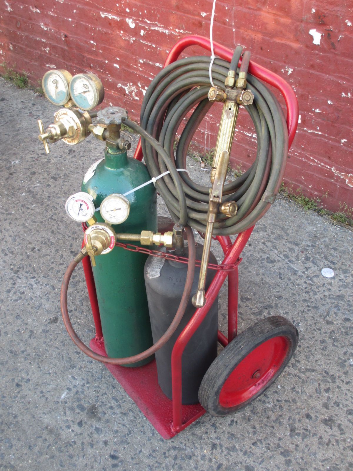 A cart with a green cylinder and a red handle
