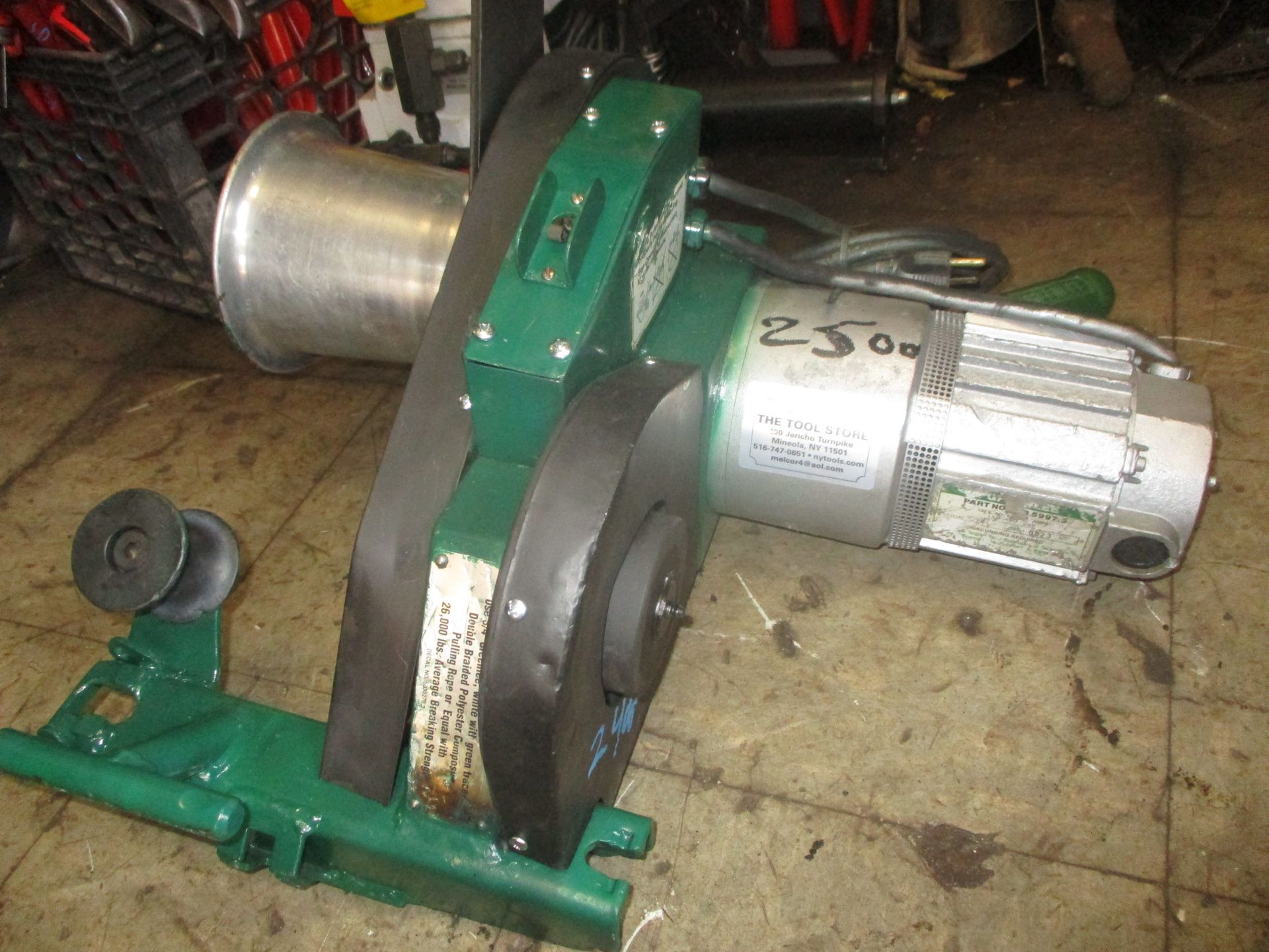 A green and silver machine is sitting on a tiled floor.