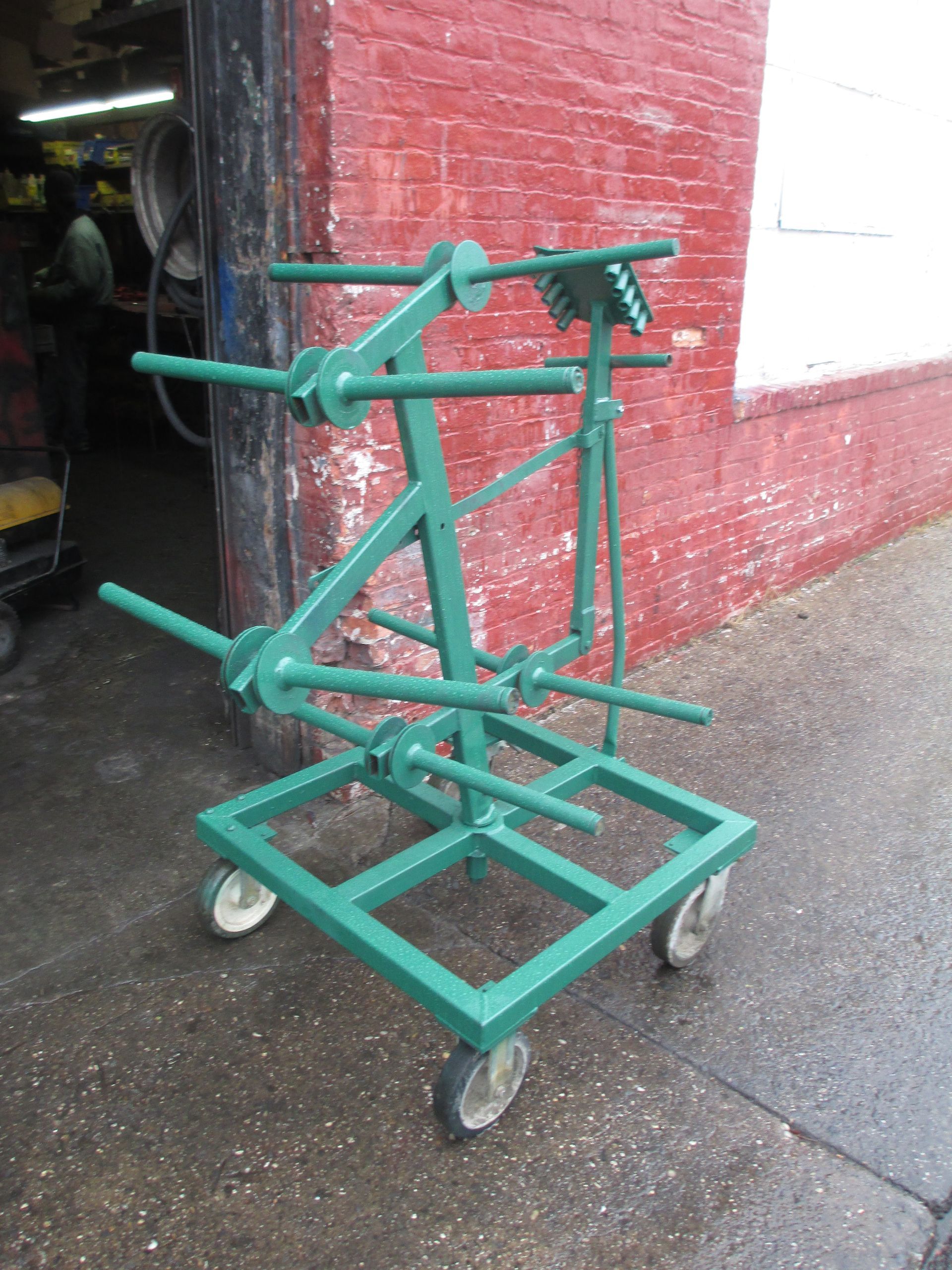 A green cart is parked in front of a red brick building