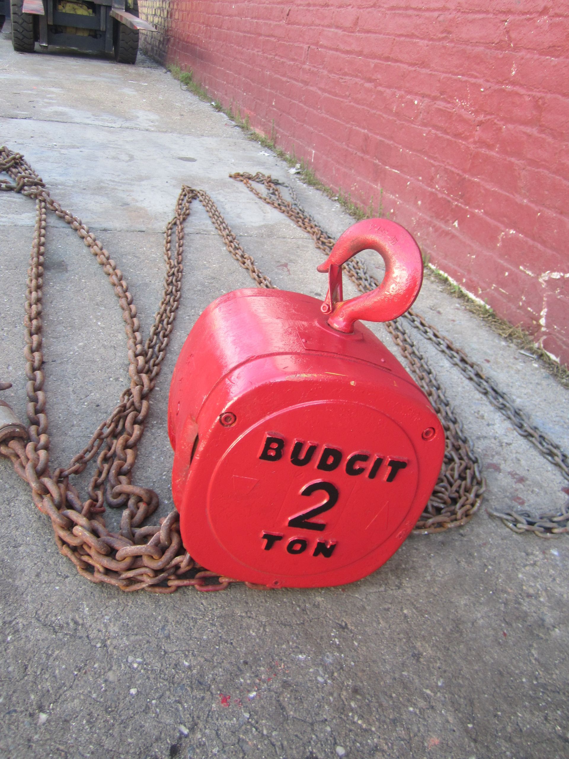 A red budcit 2 ton chain hoist with chains attached to it