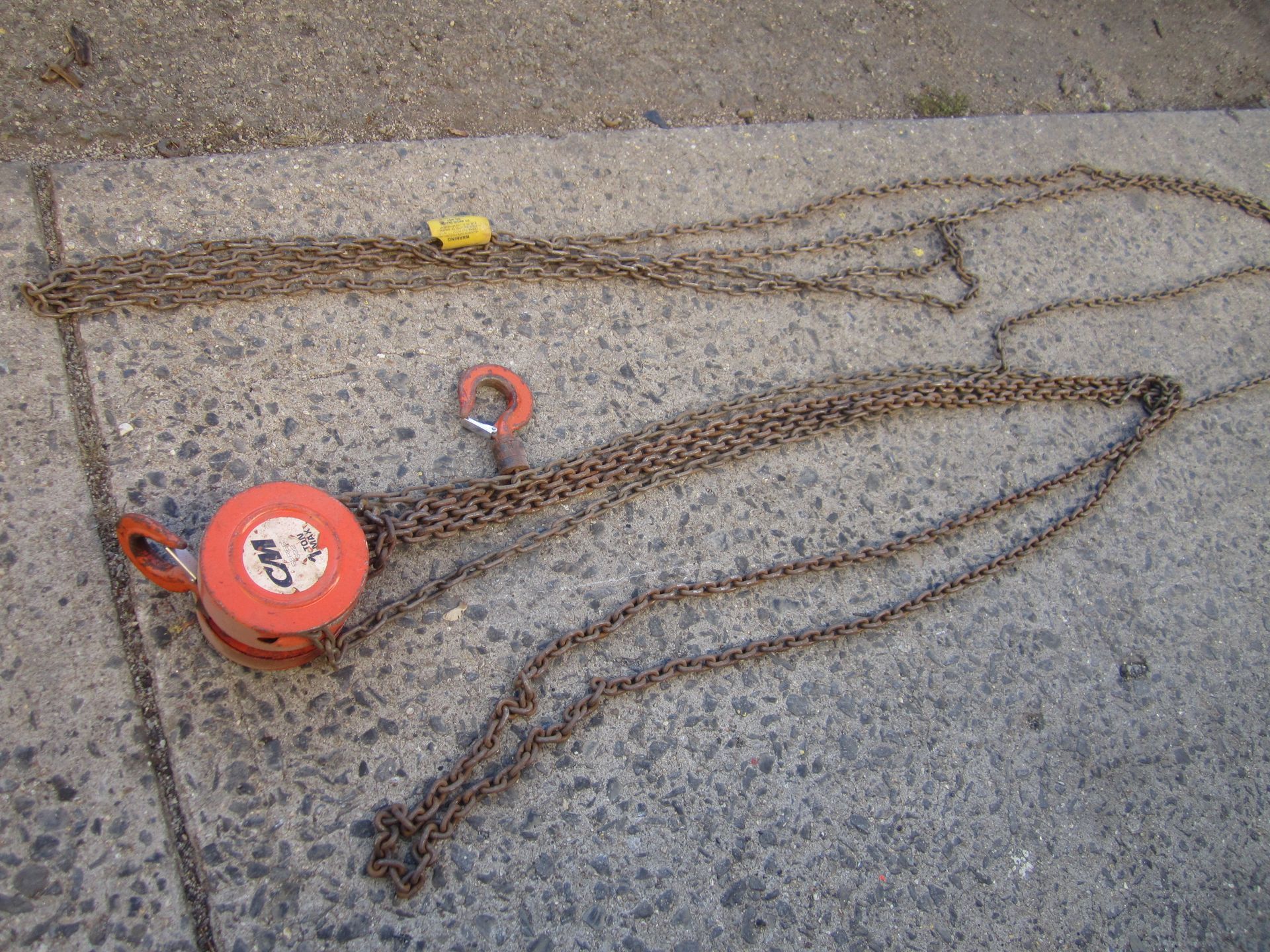 A pair of chains are laying on a concrete surface.