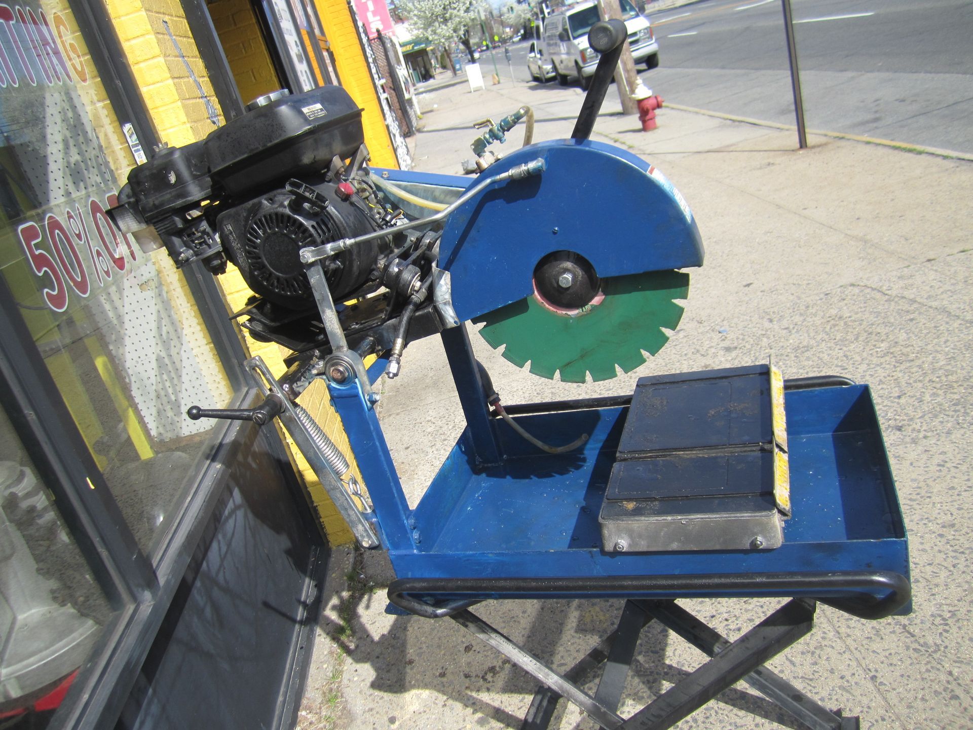 A circular saw with a green blade is sitting outside of a store