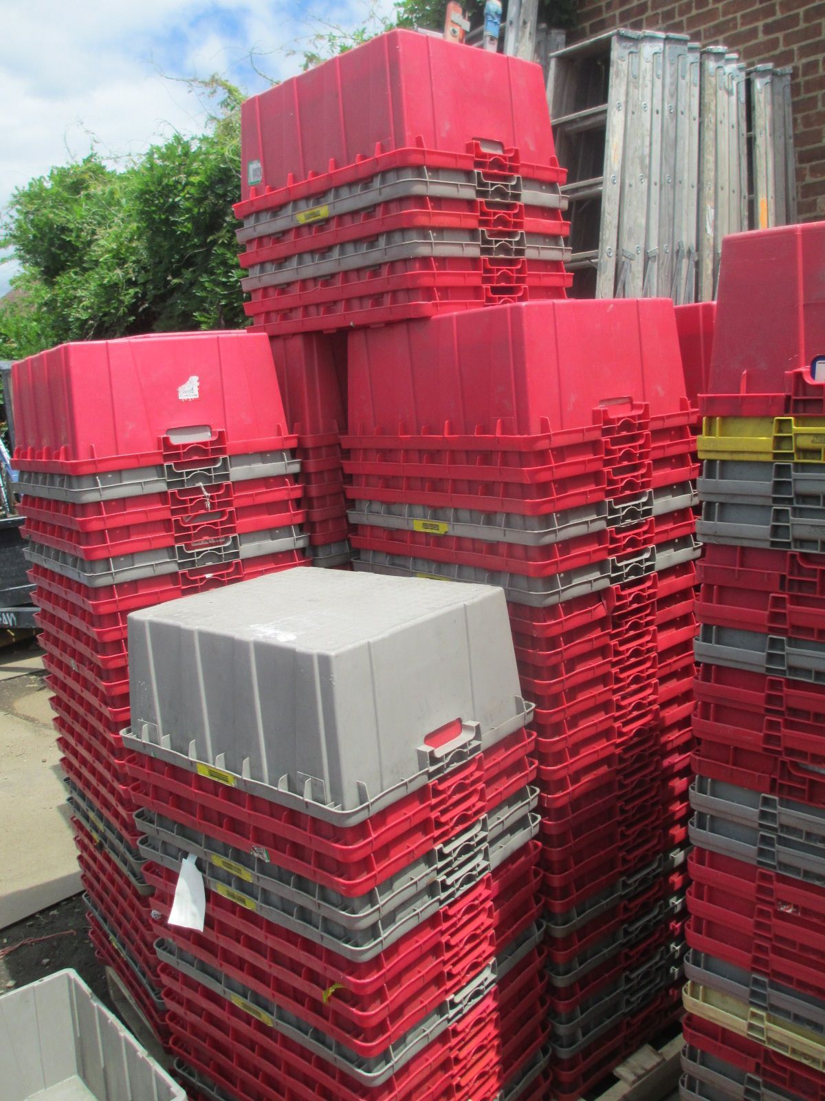 A pile of red plastic crates are stacked on top of each other.