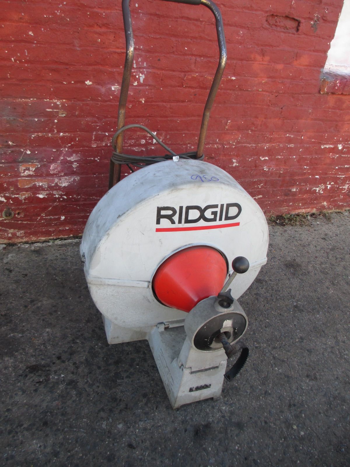 A ridgid machine is sitting in front of a red brick wall