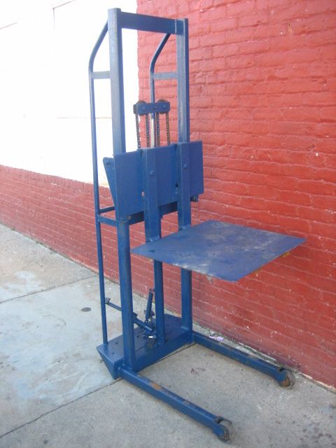 A blue forklift is sitting in front of a red brick wall