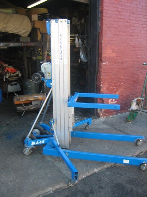 A blue aluminum lift is sitting in front of a red brick building