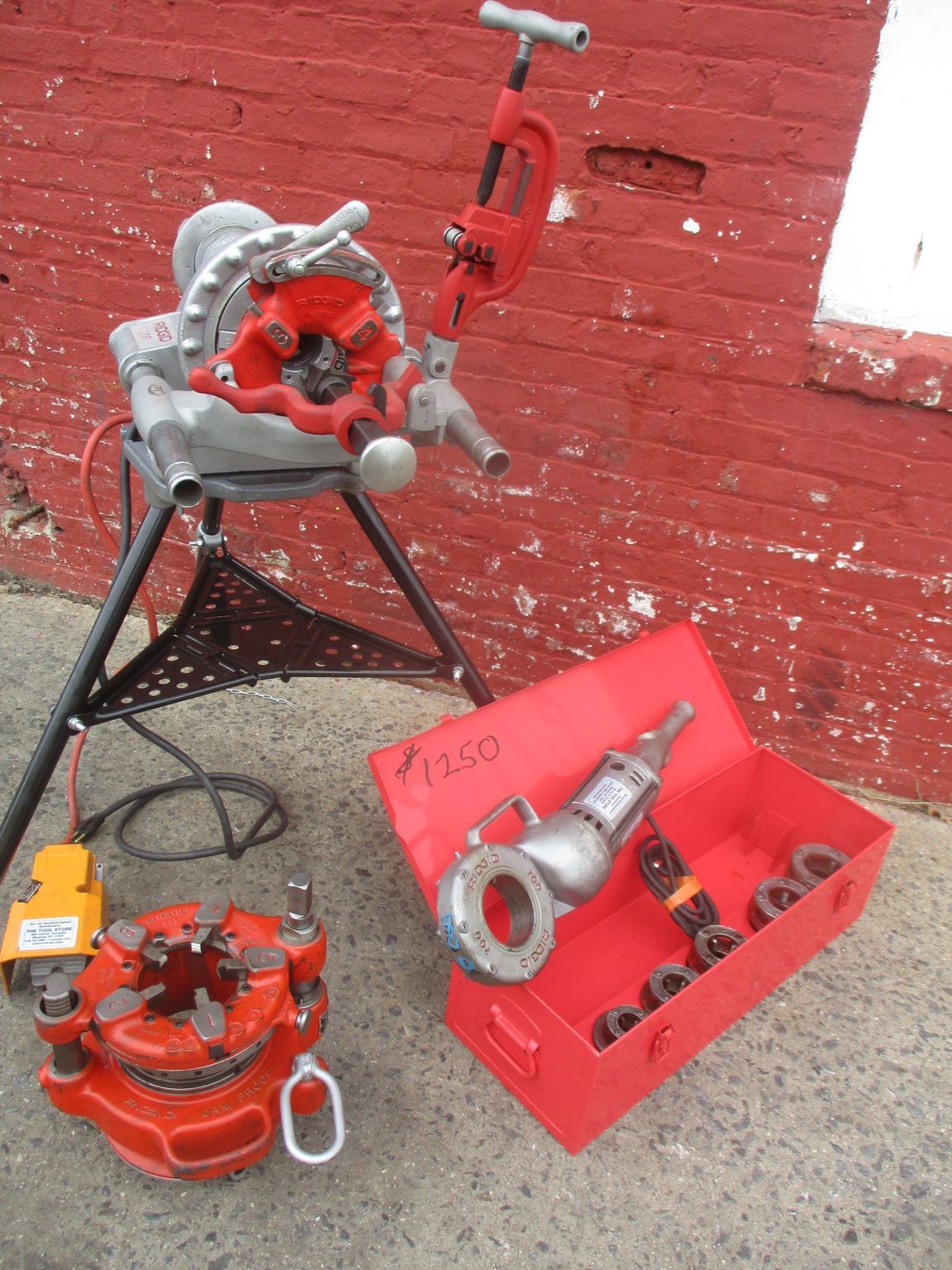 A red toolbox with a drill and a pipe cutting machine