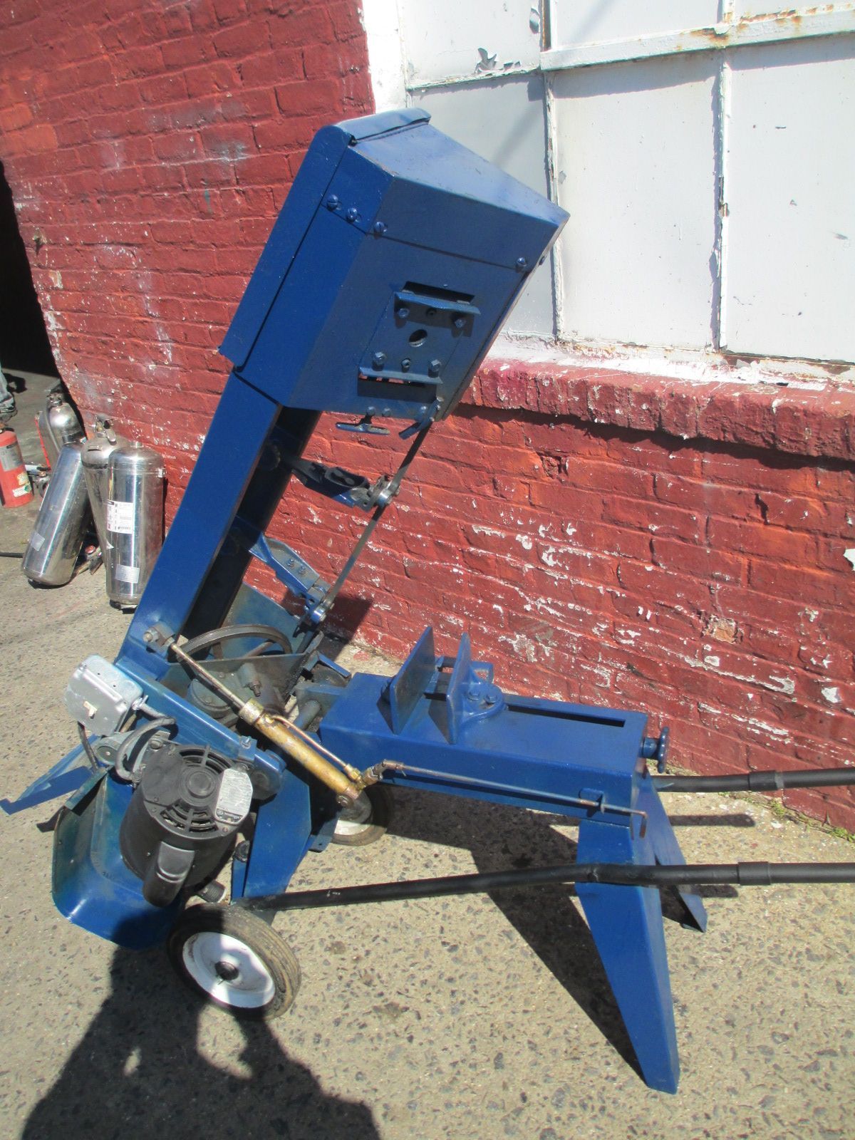 A blue machine is sitting in front of a red brick wall