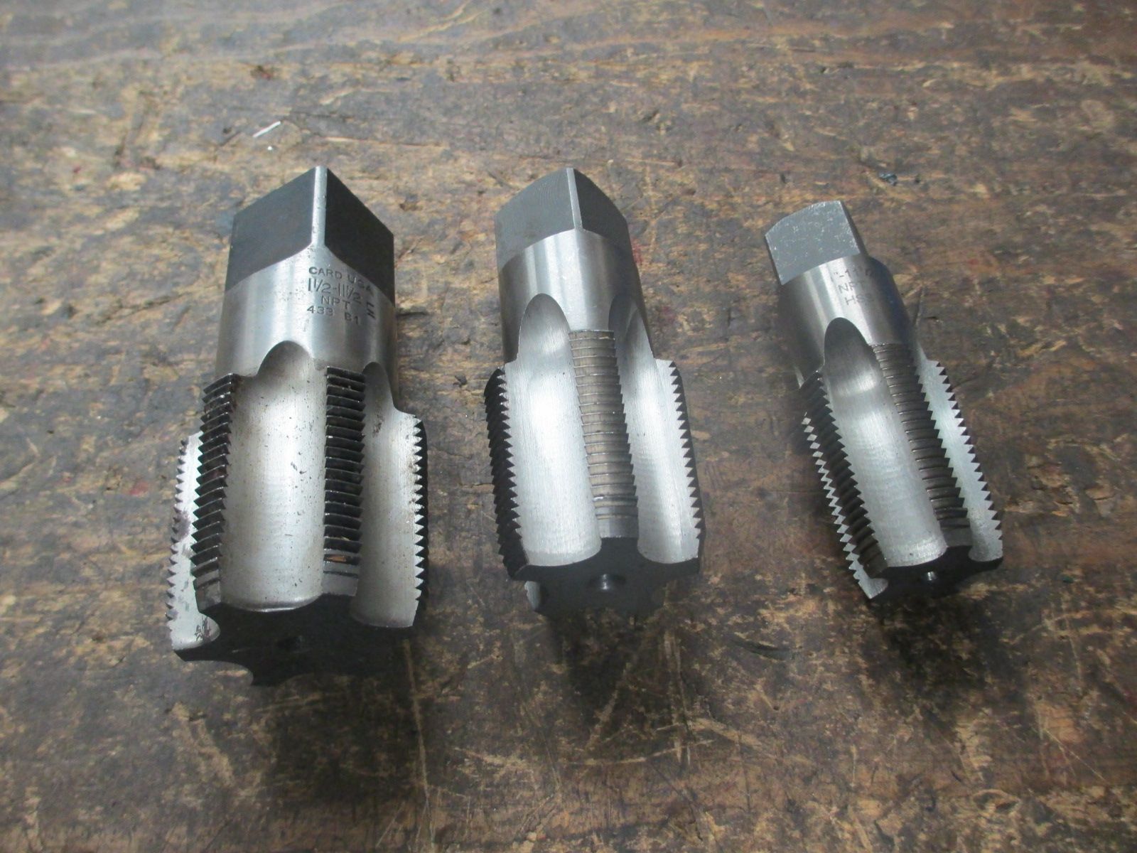 Three drill bits are sitting on a wooden table