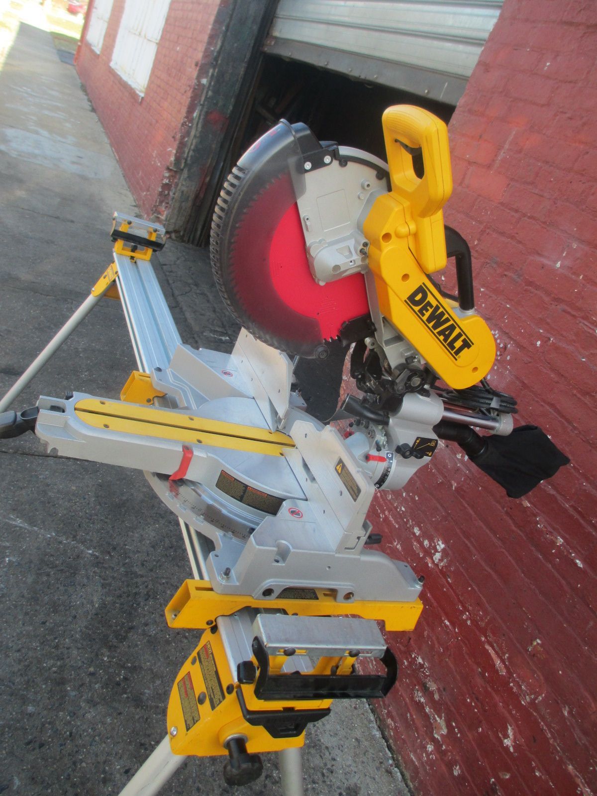 A dewalt circular saw is sitting on a tripod in front of a brick building