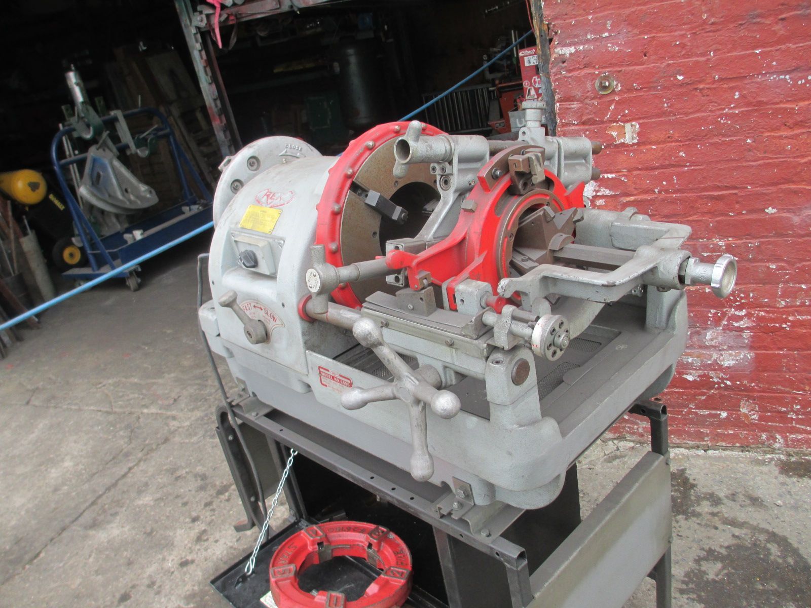 A machine is sitting on a cart in front of a brick wall.