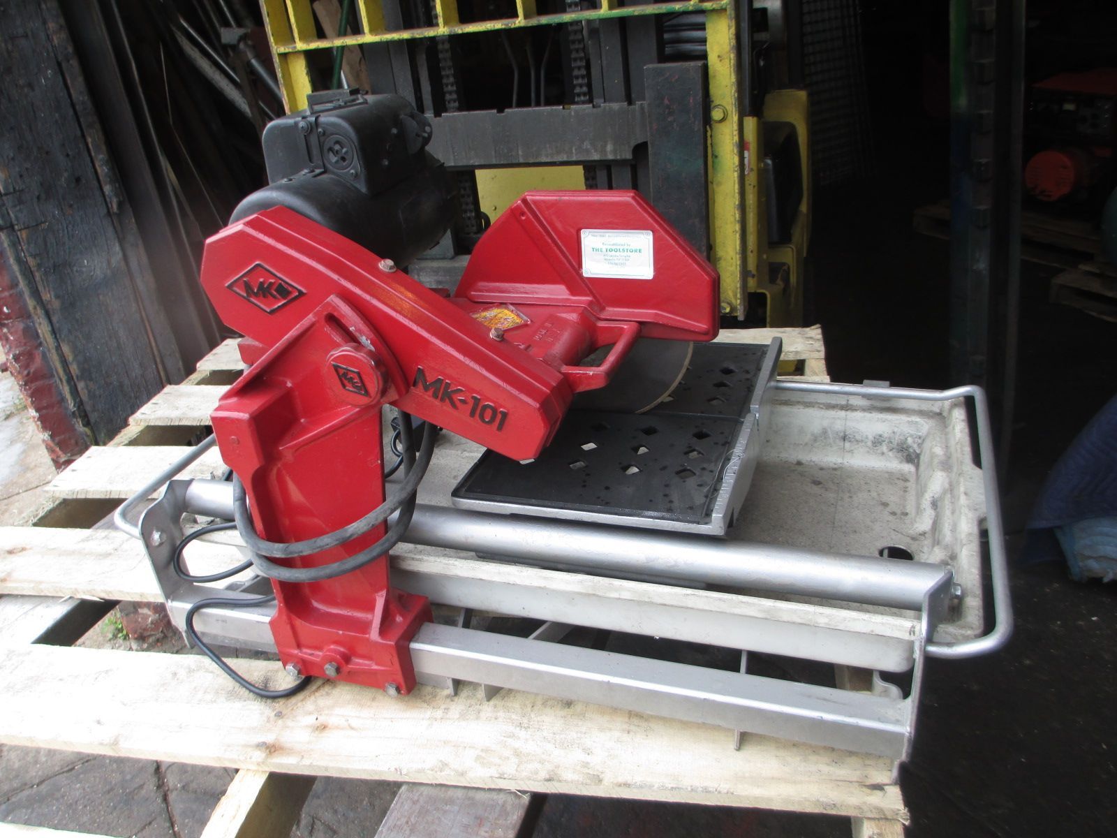 A red tile saw is sitting on a wooden pallet