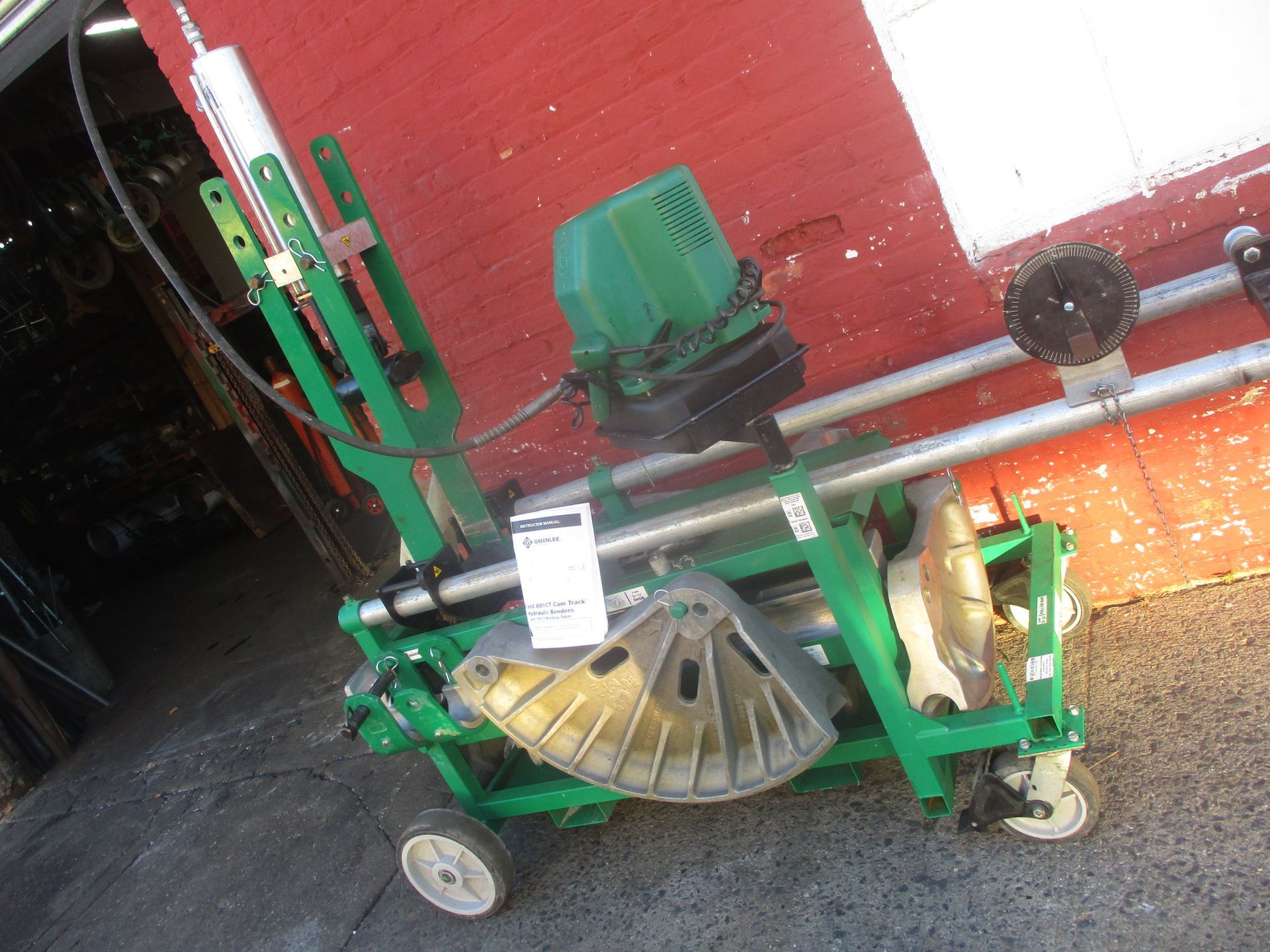 A green machine is sitting in front of a red building