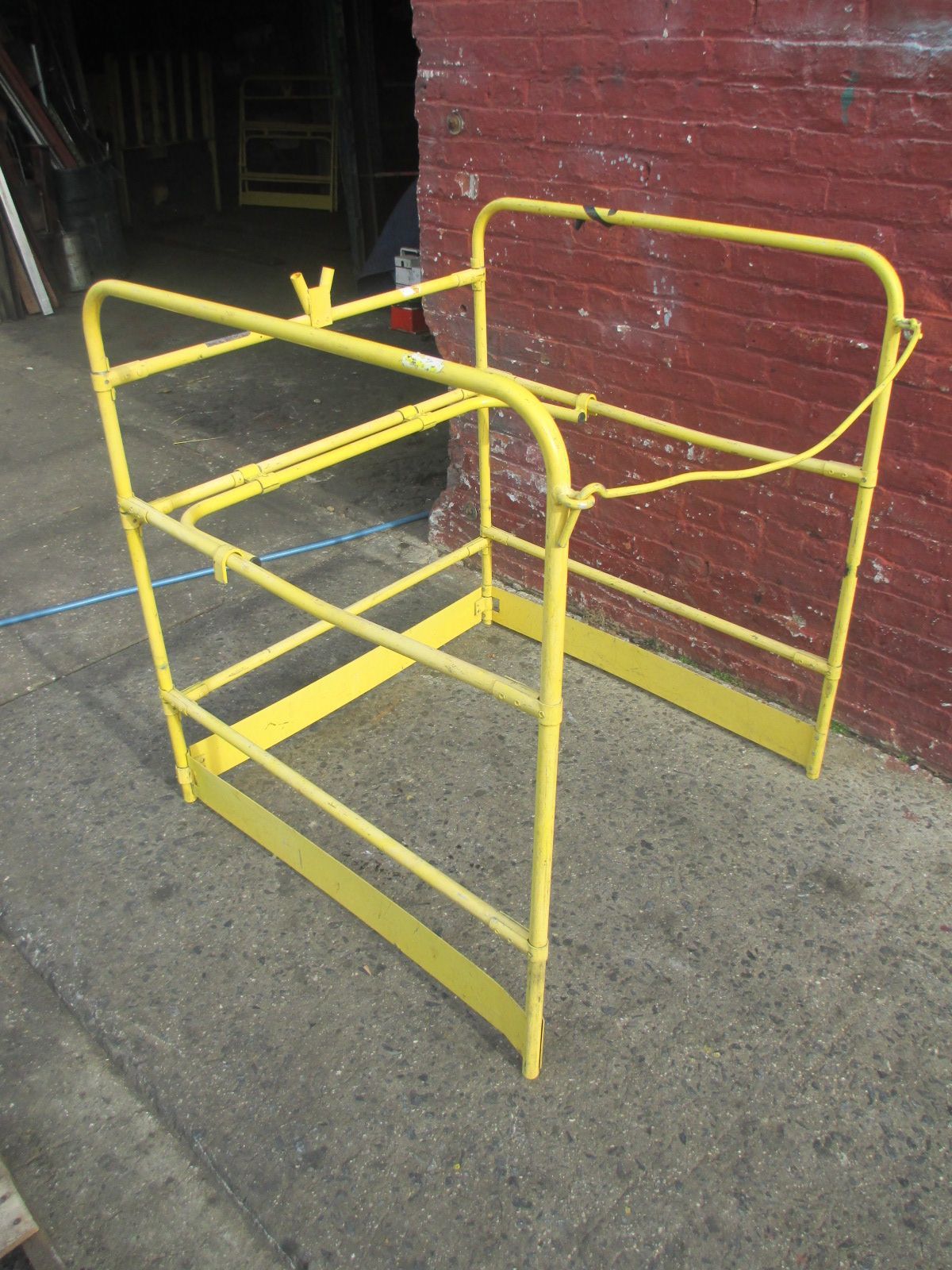 A yellow metal structure is sitting in front of a red brick wall