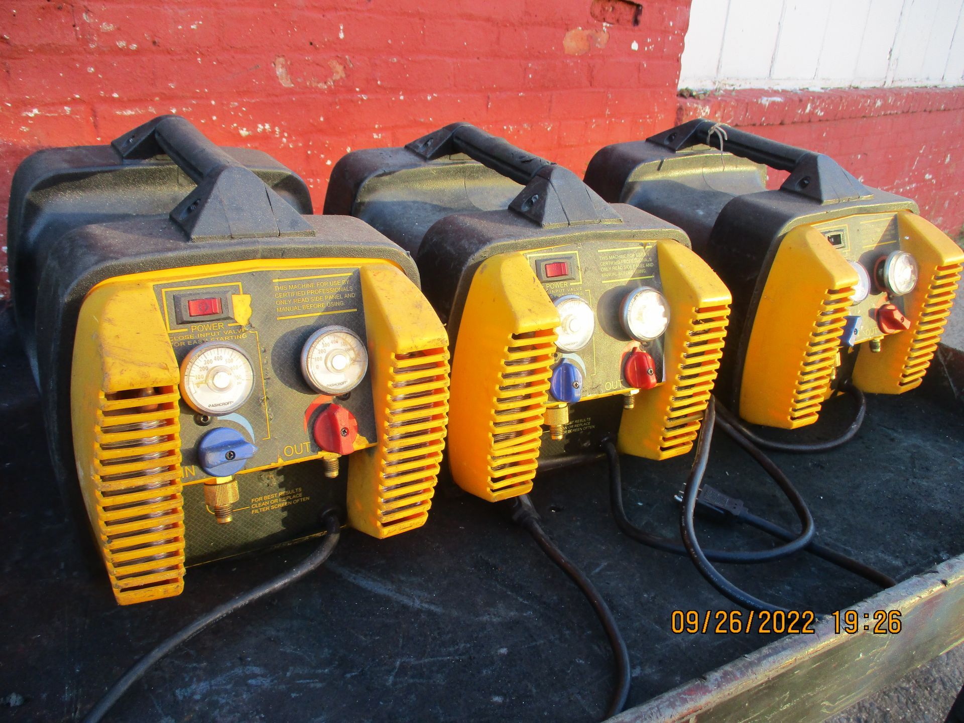 Three yellow and black machines are lined up on a table.