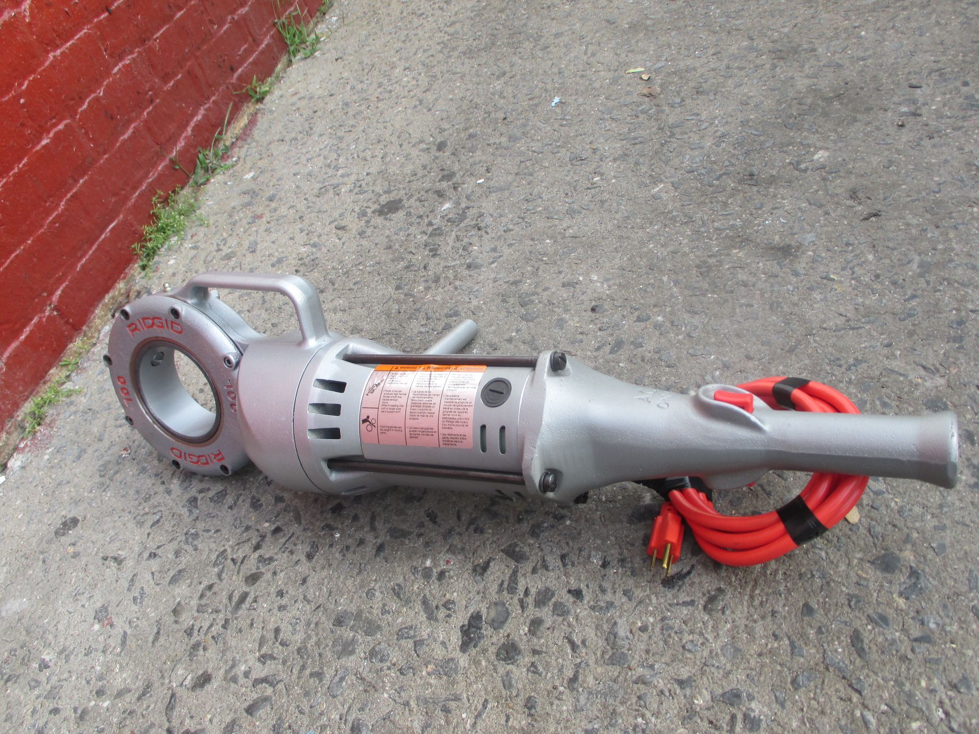 A vacuum cleaner is sitting on the ground next to a brick wall.
