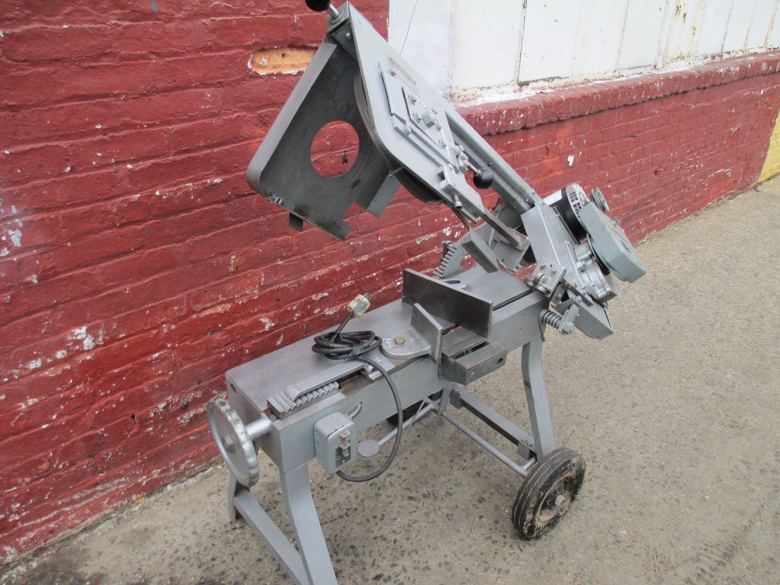 A machine is sitting on the ground in front of a brick wall