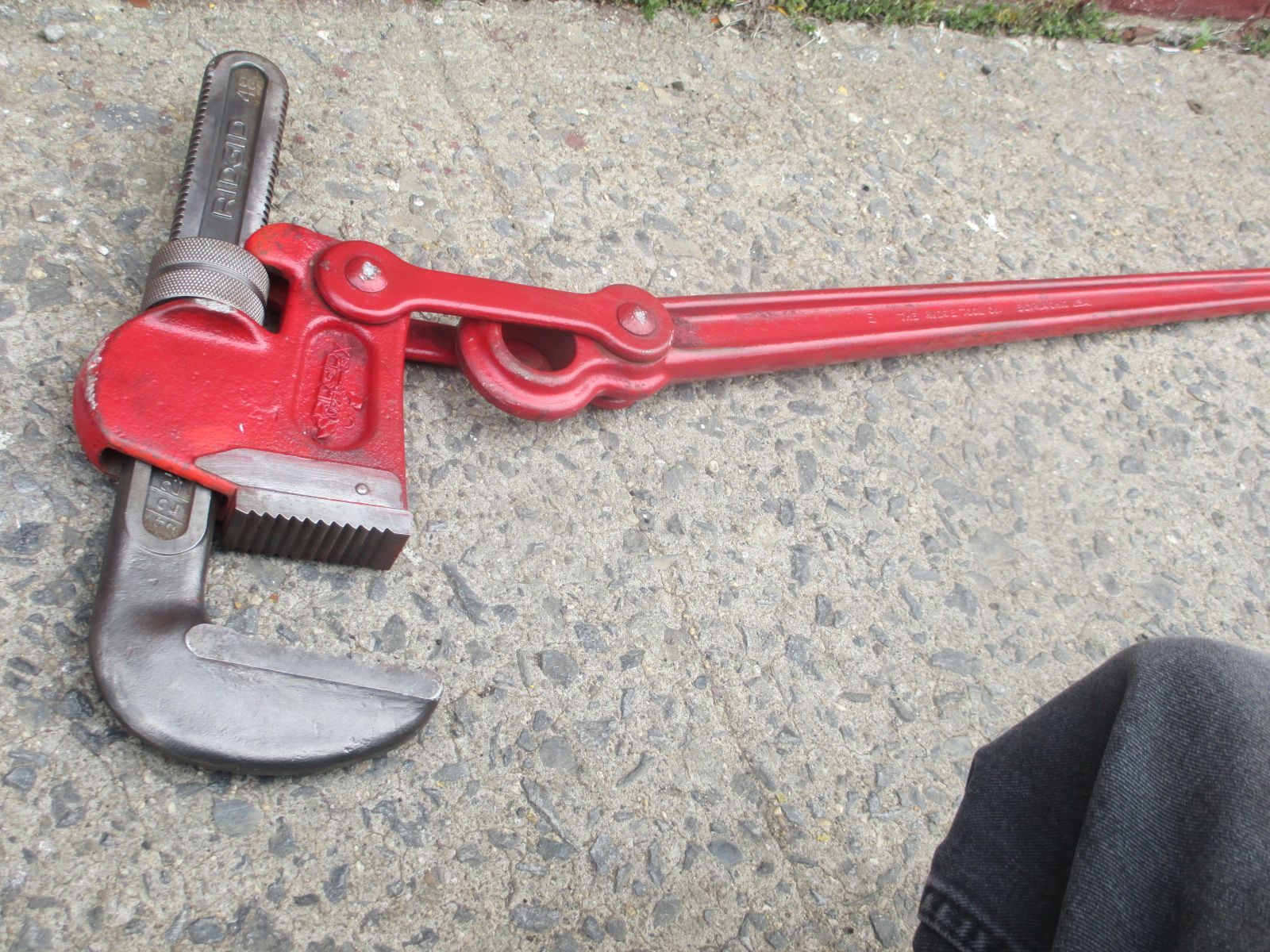 A red pipe wrench is laying on the ground