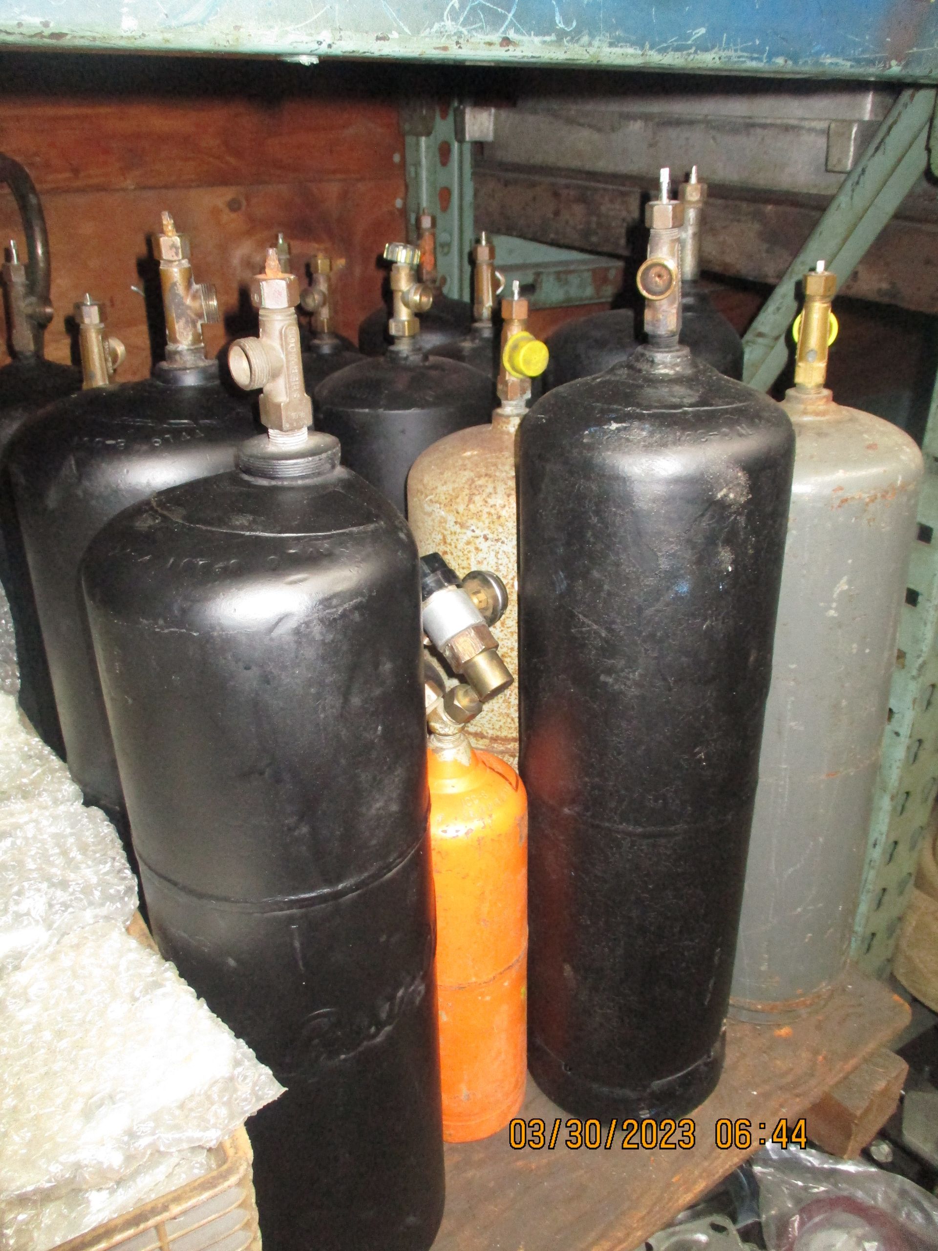 A bunch of gas cylinders are lined up on a shelf
