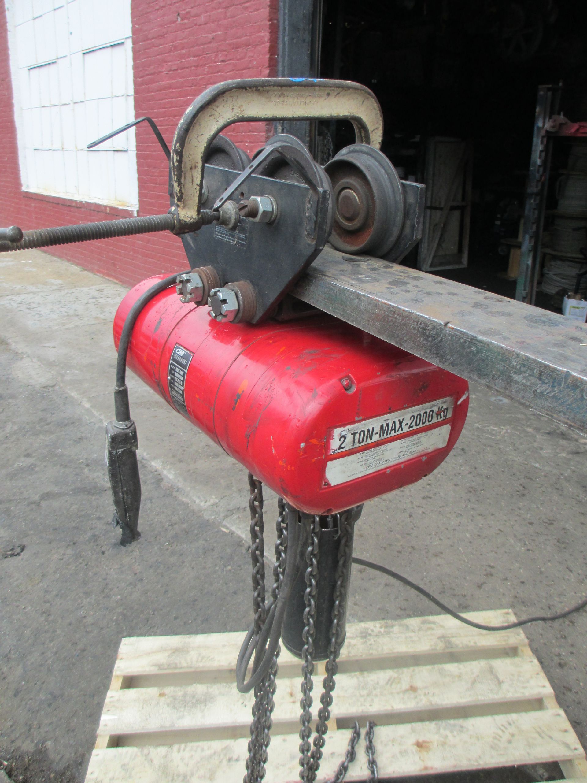 A red chain hoist is sitting on top of a wooden pallet.