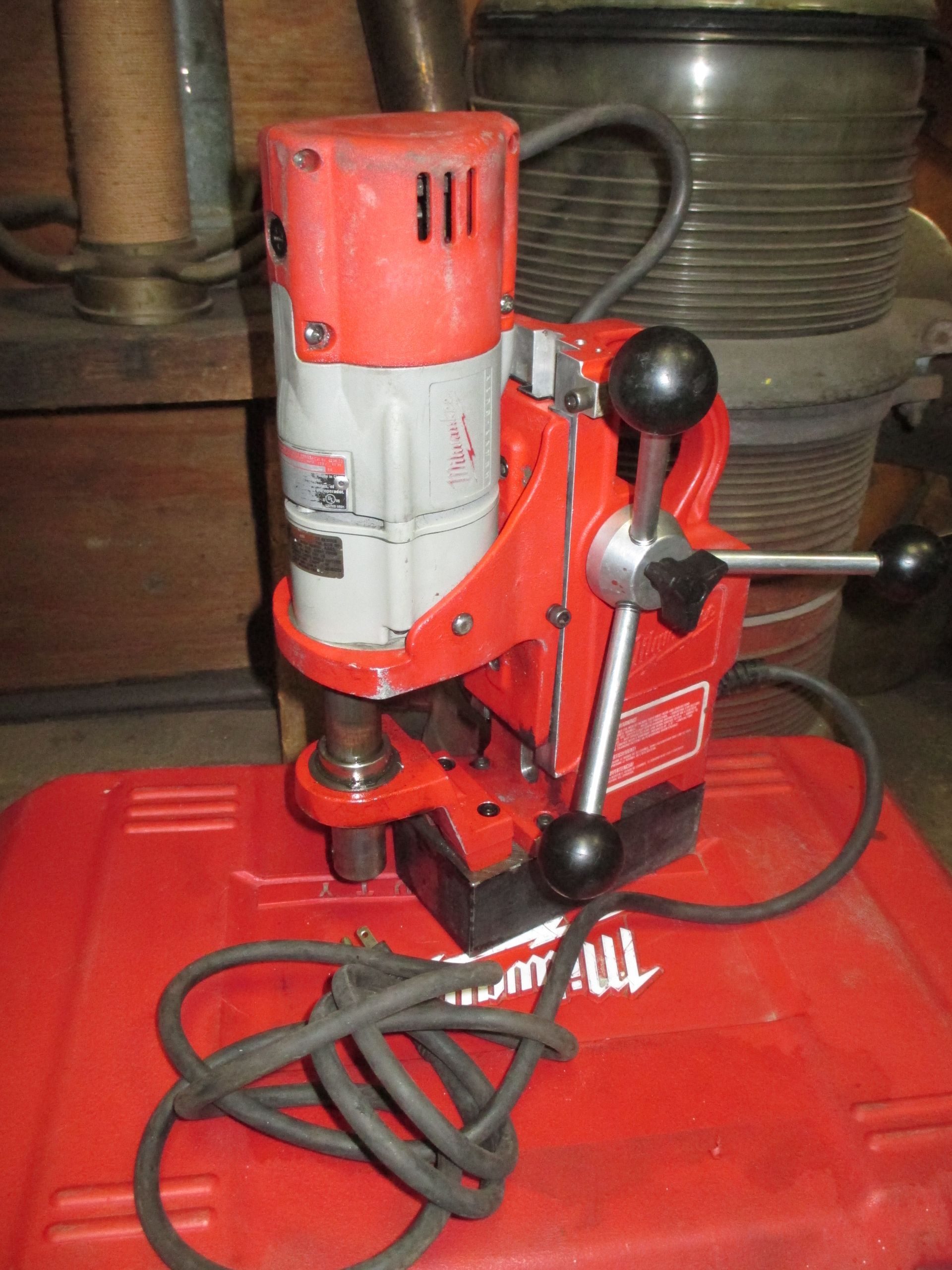 A milwaukee drill is sitting on top of a red box