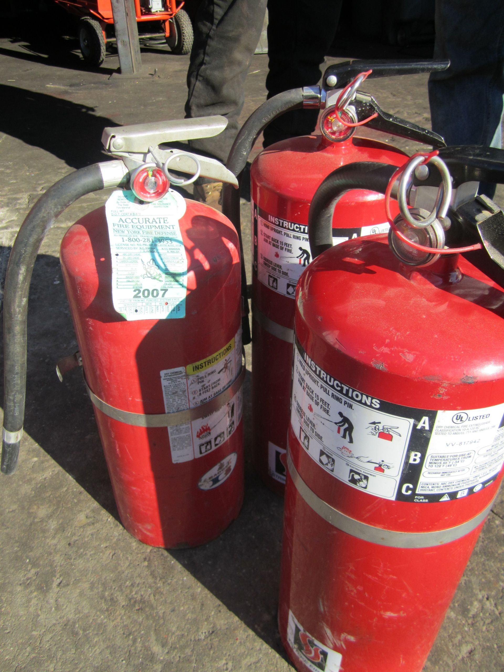 Two red fire extinguishers are sitting on the ground