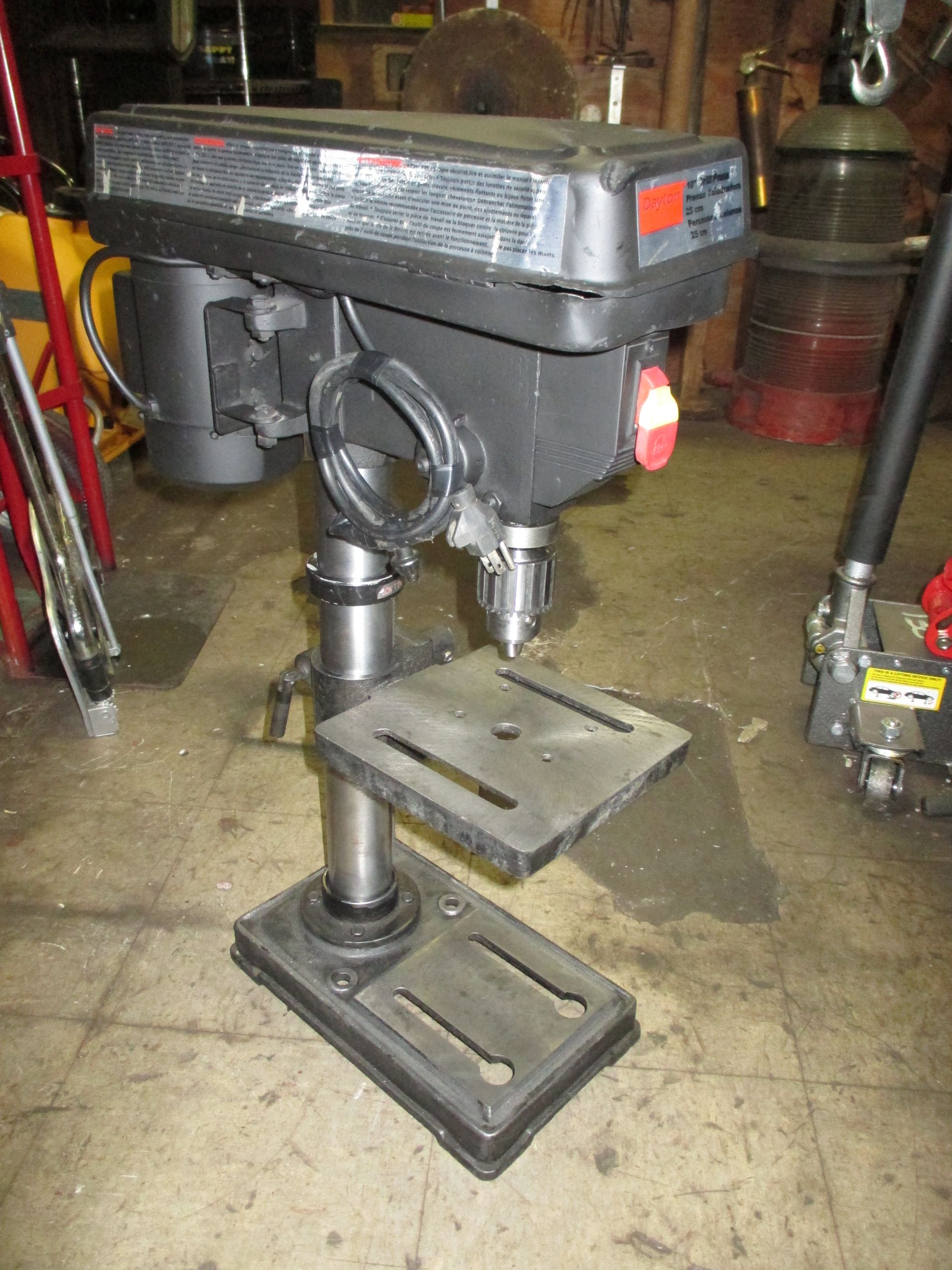 A drill press is sitting on the floor in a garage