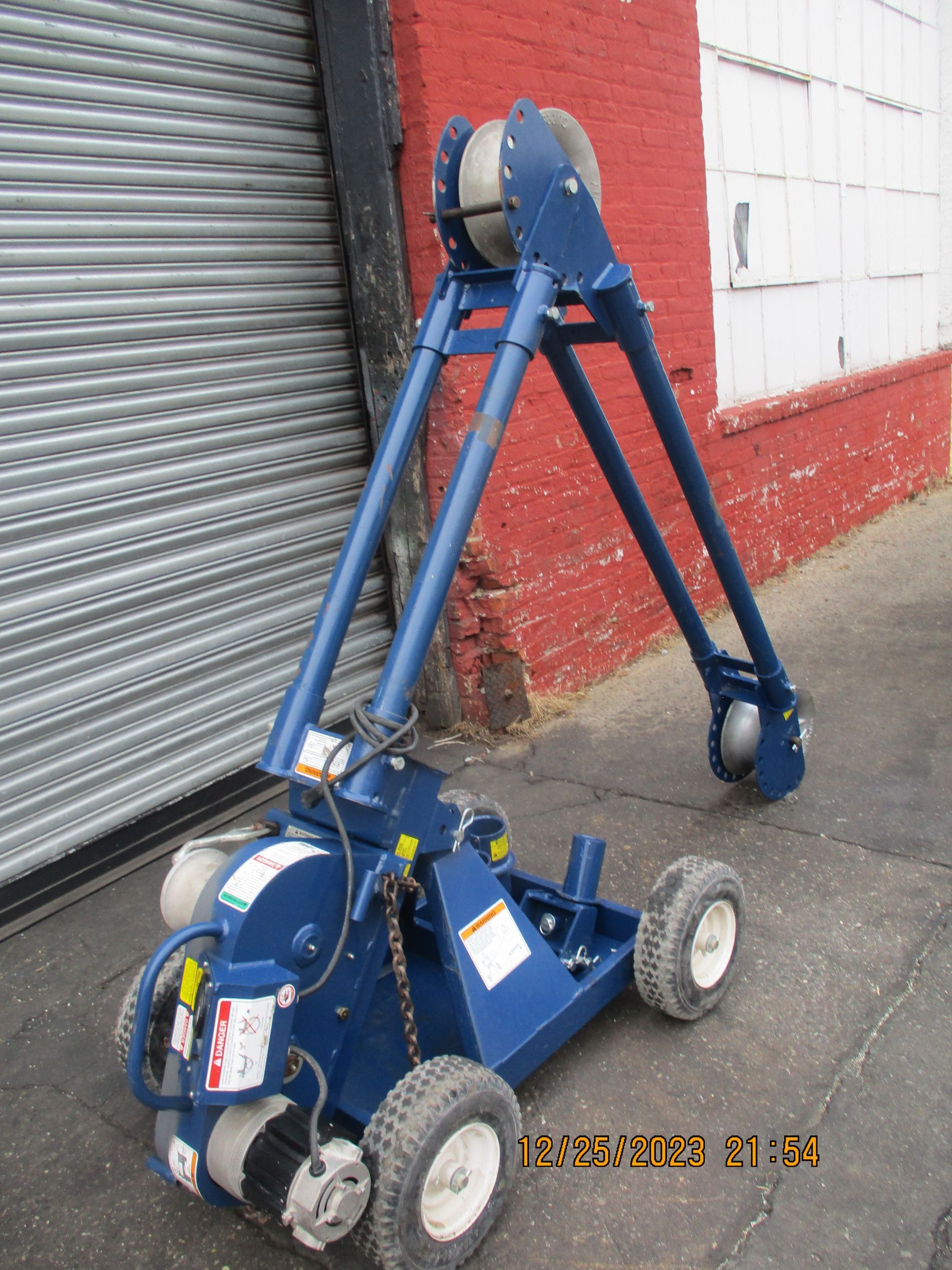 A blue machine is parked in front of a red brick building