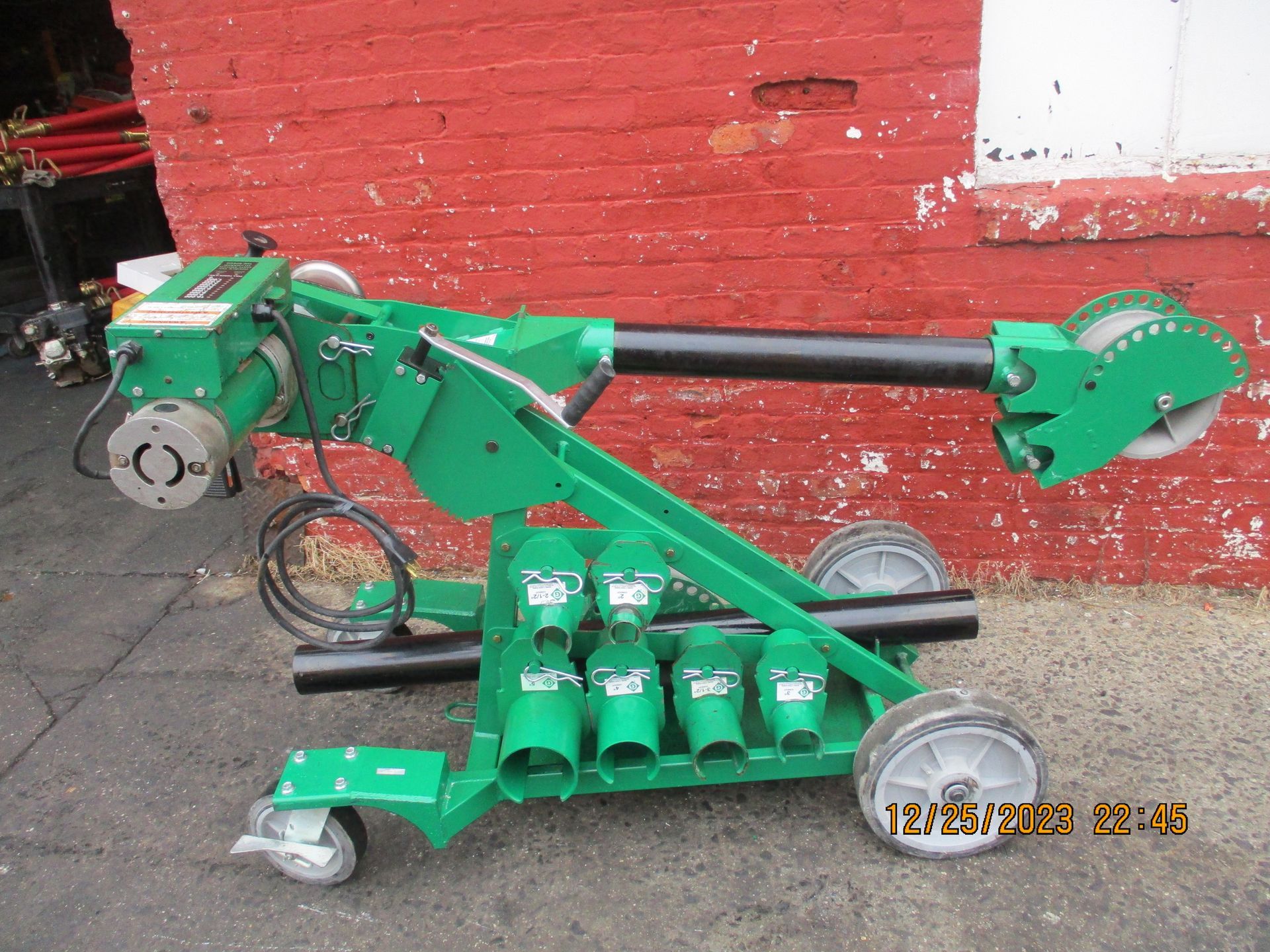 A green machine is sitting in front of a red brick wall