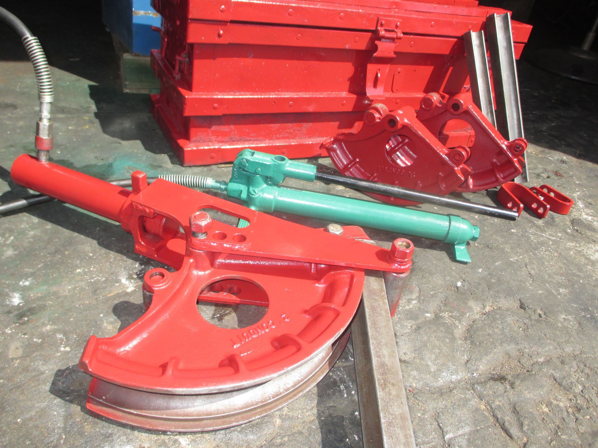 A red pipe bending machine is sitting on a wooden table