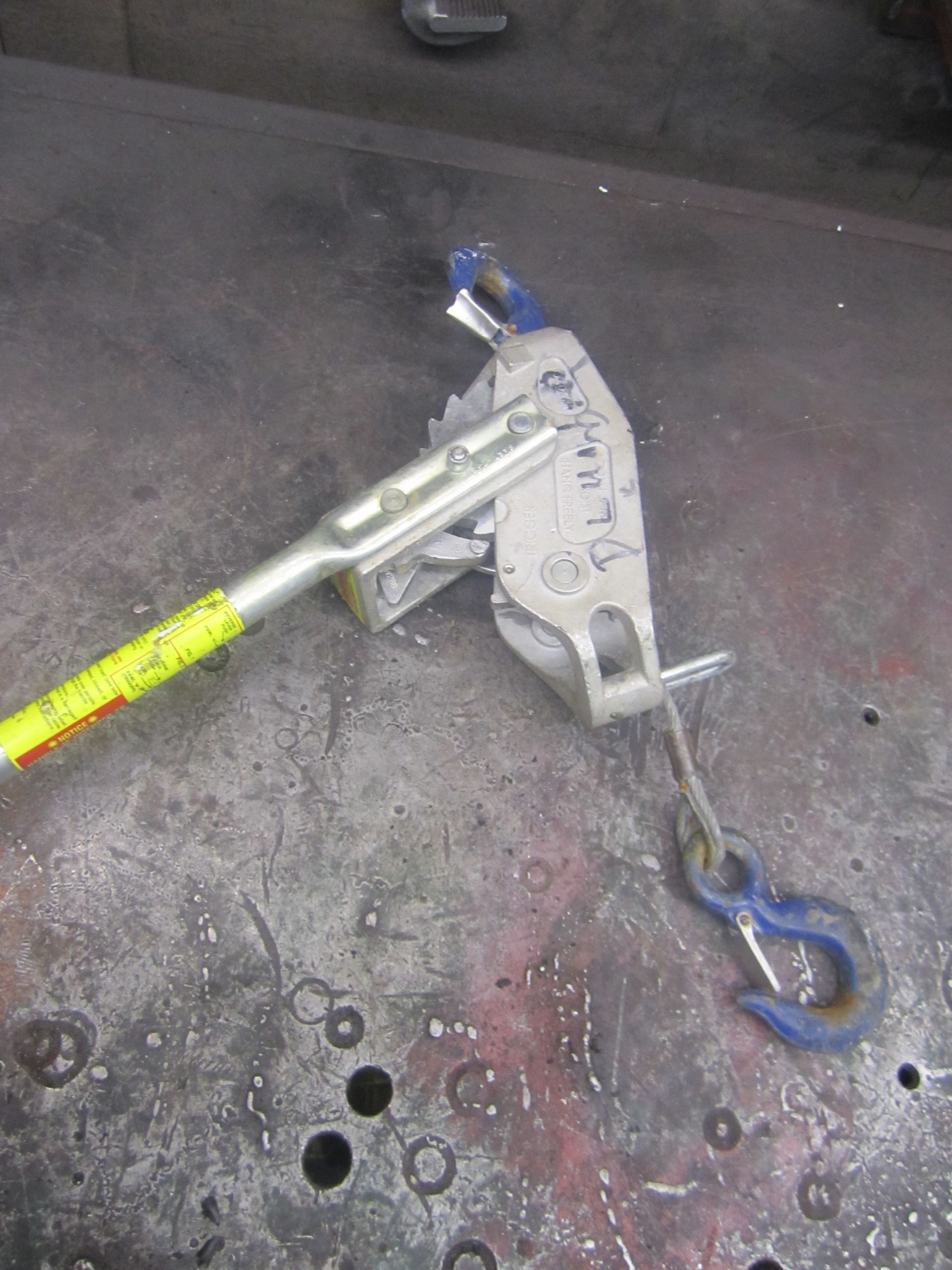 A tool with a hook attached to it is sitting on a table.