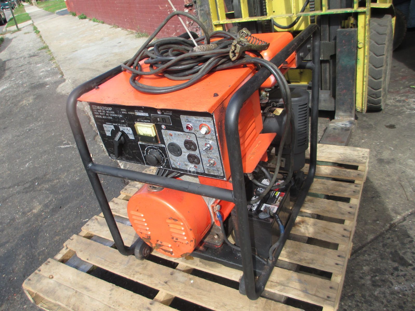 An orange generator is sitting on a wooden pallet