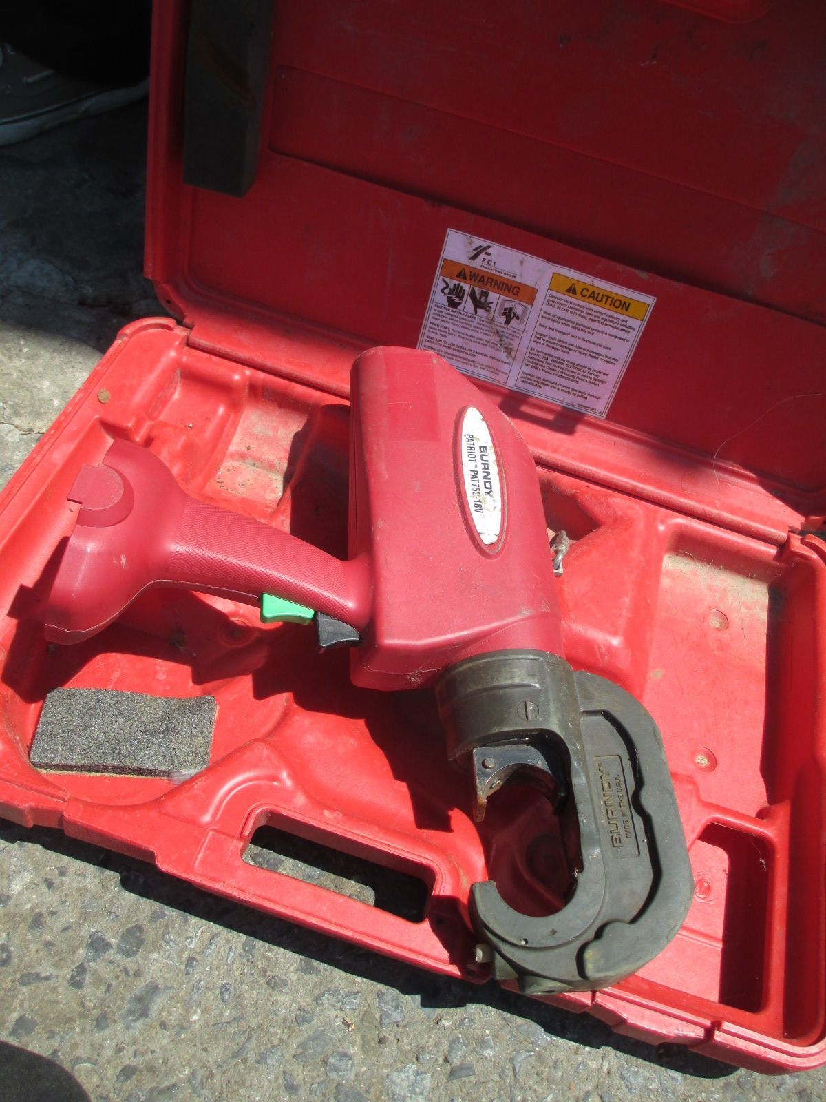 A red tool in a red case with a warning label on it