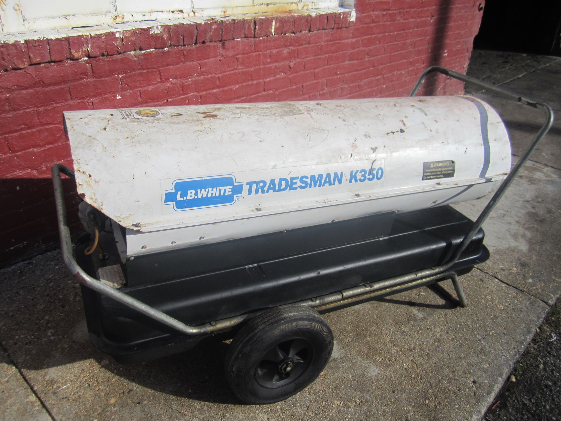 A tradesman heater is sitting in front of a red brick building