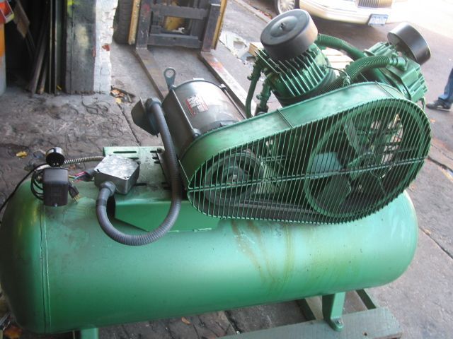 A green air compressor with a fan attached to it