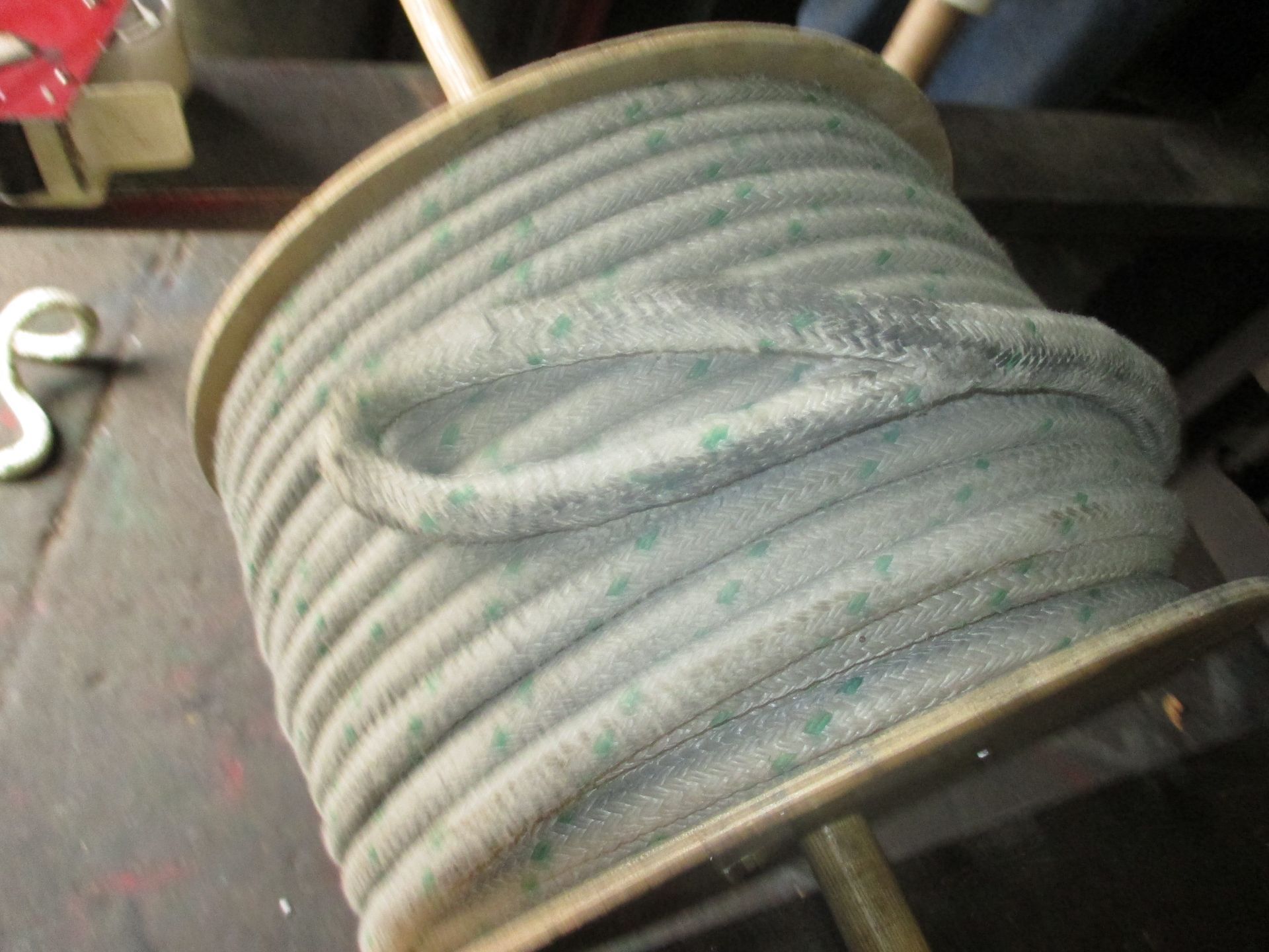 A spool of wire is sitting on a wooden spool on a table.
